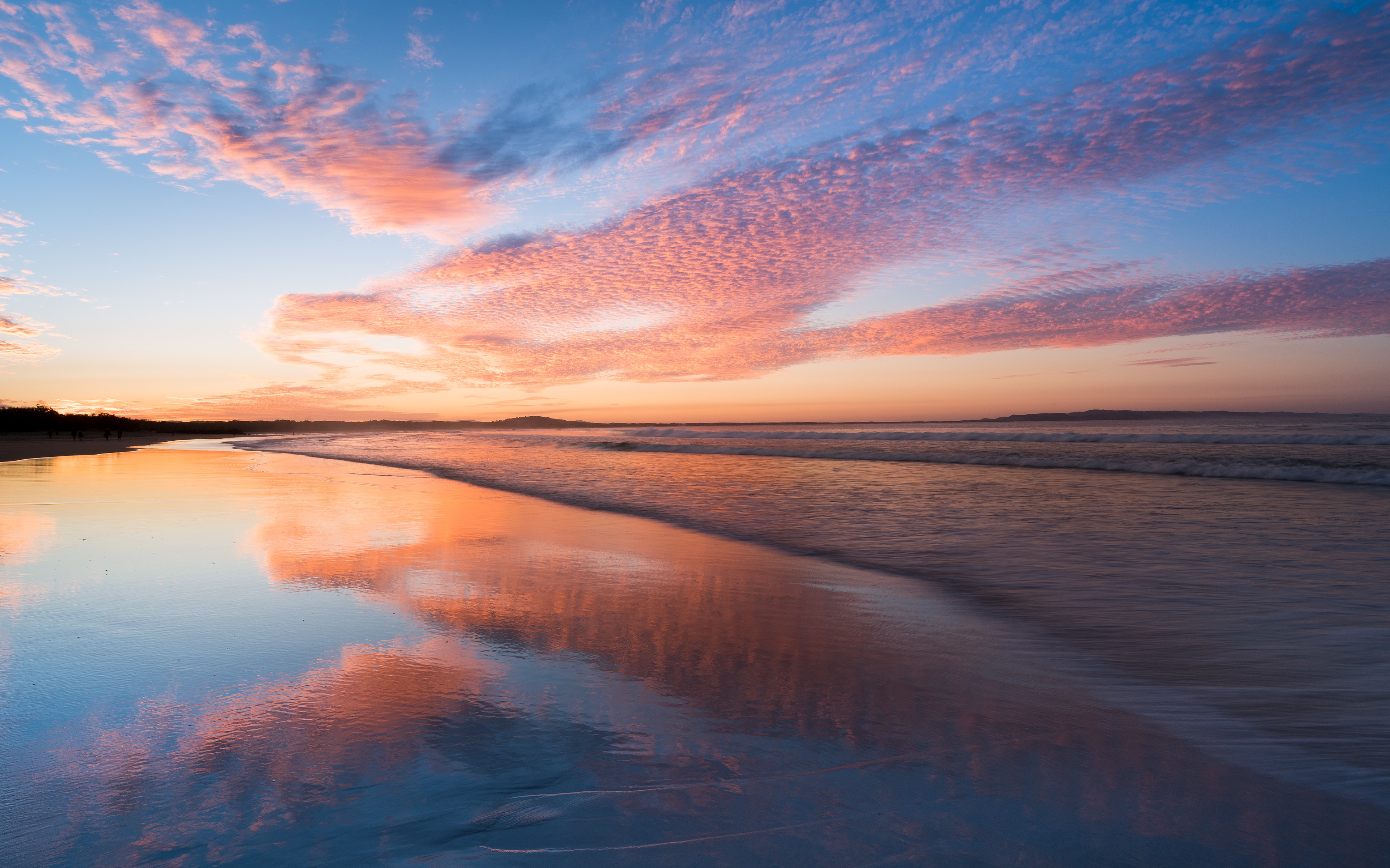 Sunset over a beach with pink clouds and ocean waves HD Wallpaper