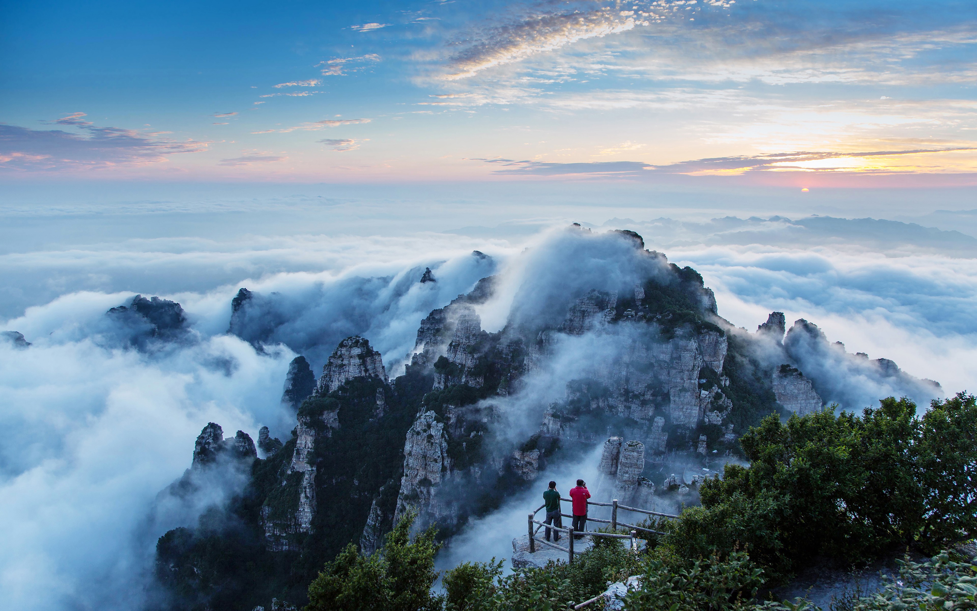 Mountains shrouded in clouds at sunrise HD Wallpaper