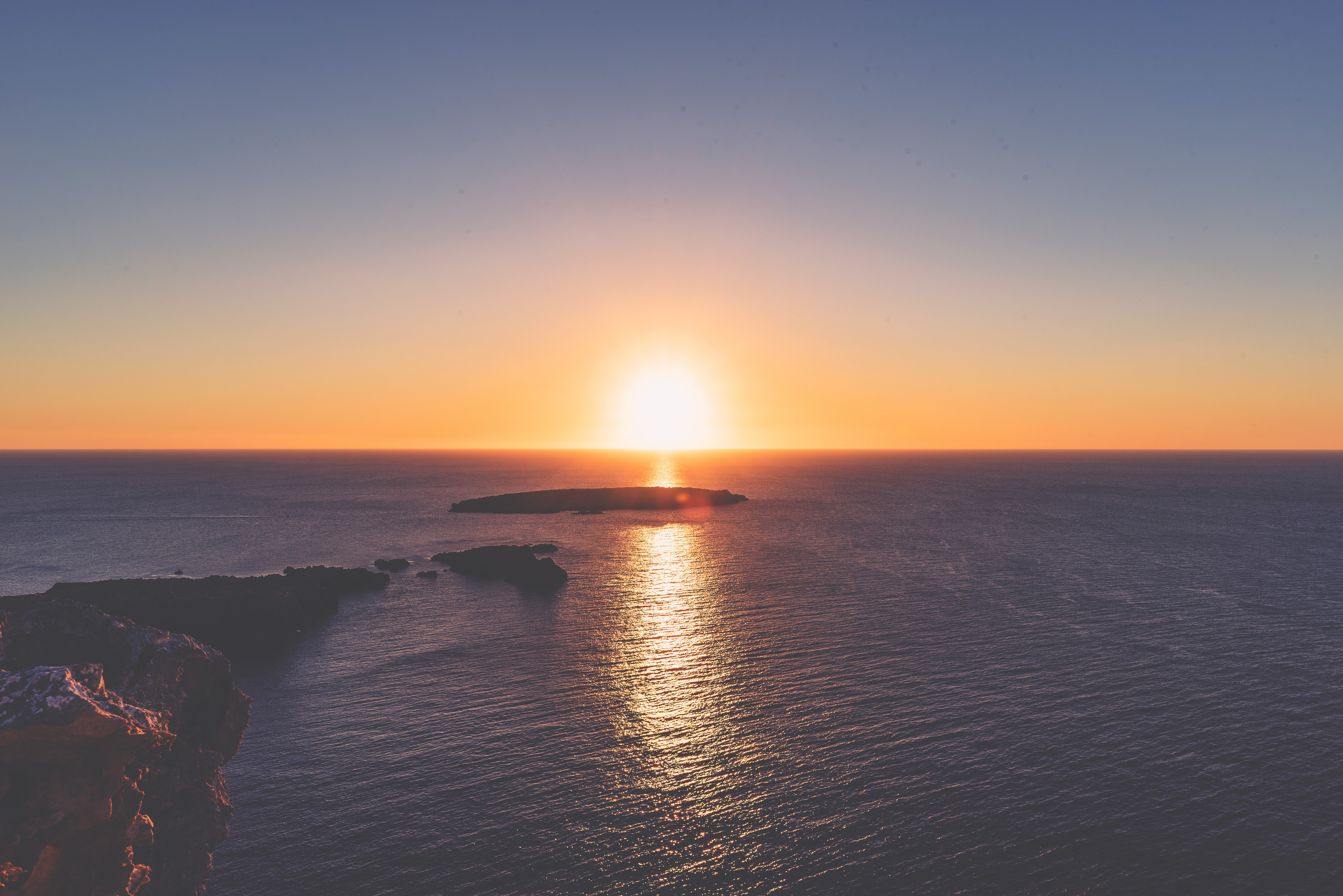 Sunset over the ocean with islands and cliffs HD Wallpaper