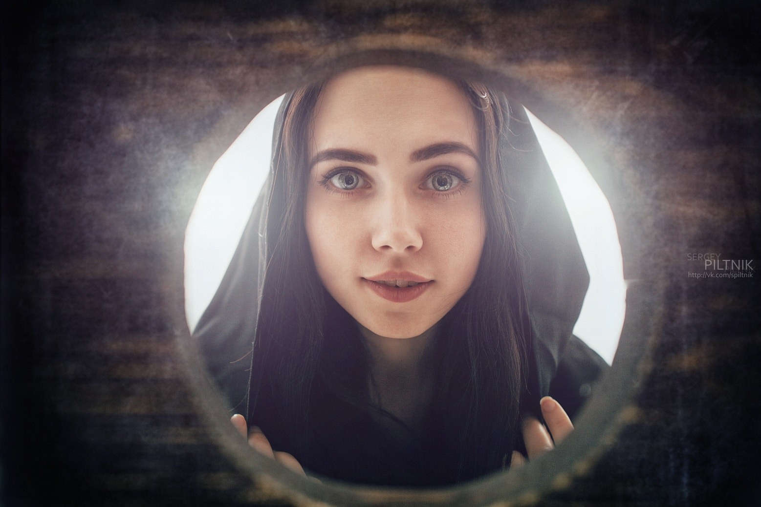 Woman wearing a black hood looking through a circular opening HD Wallpaper