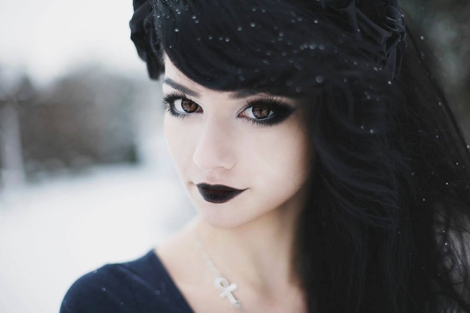 Woman with dark hair and dark lipstick in snow HD Wallpaper