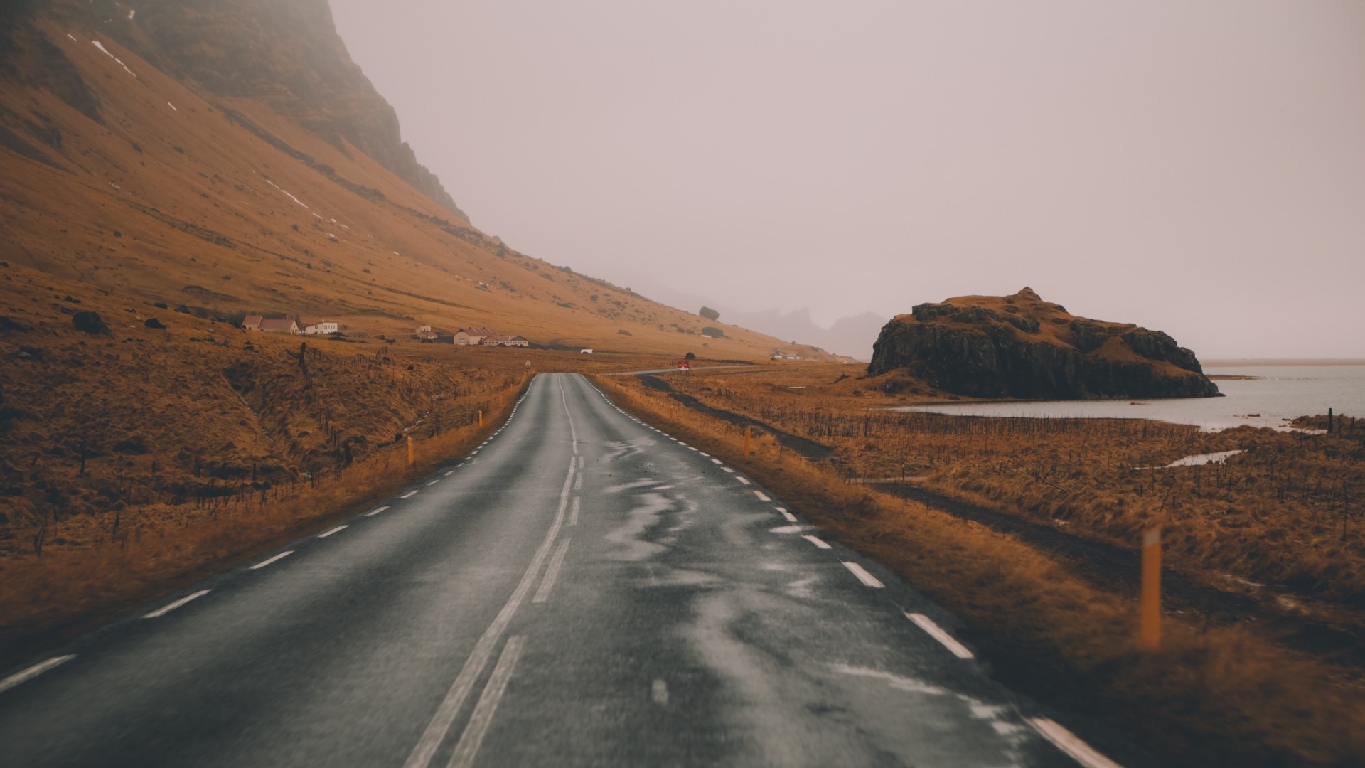 Road through a mountainous landscape with villages and a rock formation HD Wallpaper