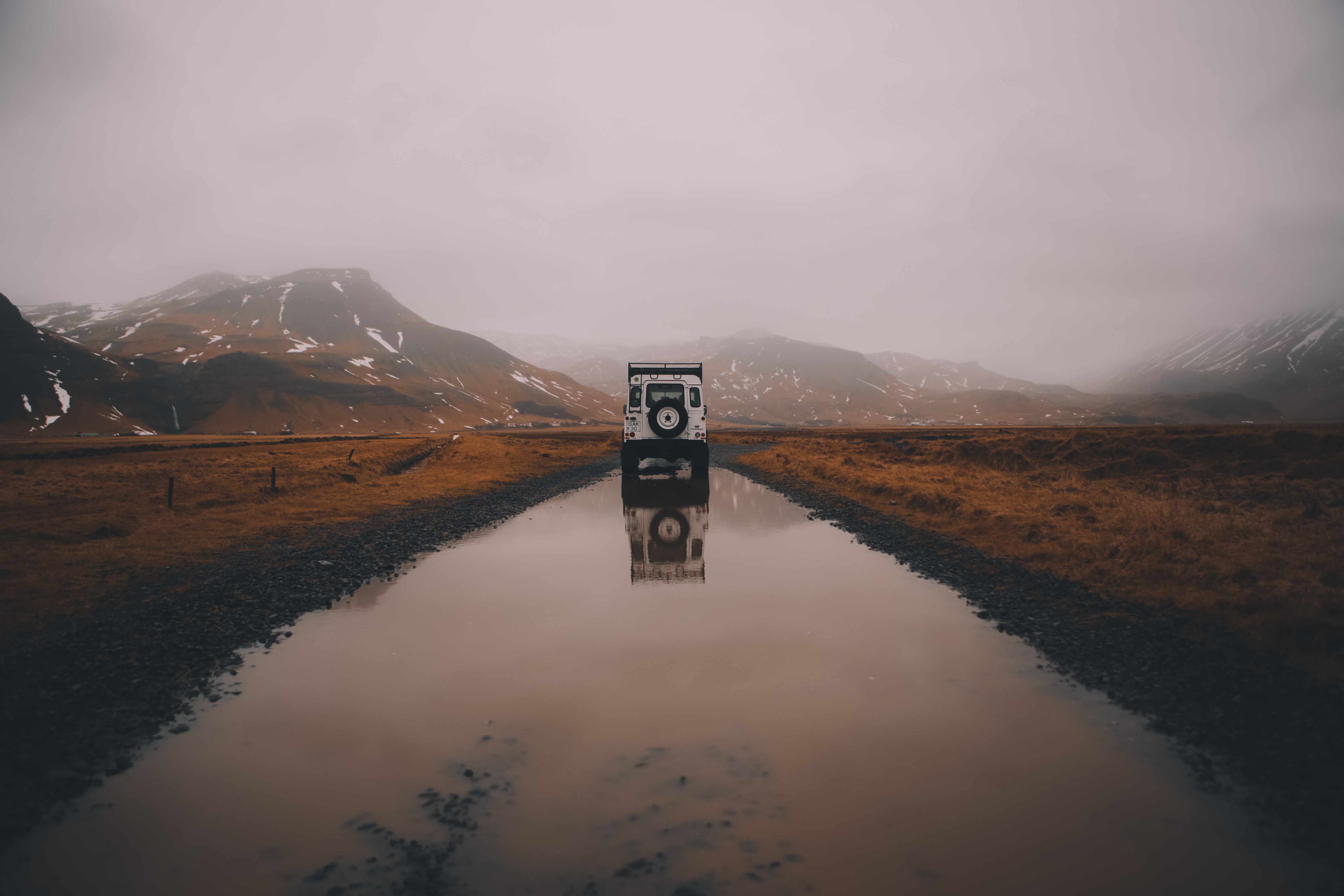 White SUV reflected in a flooded road with mountains in the background HD Wallpaper