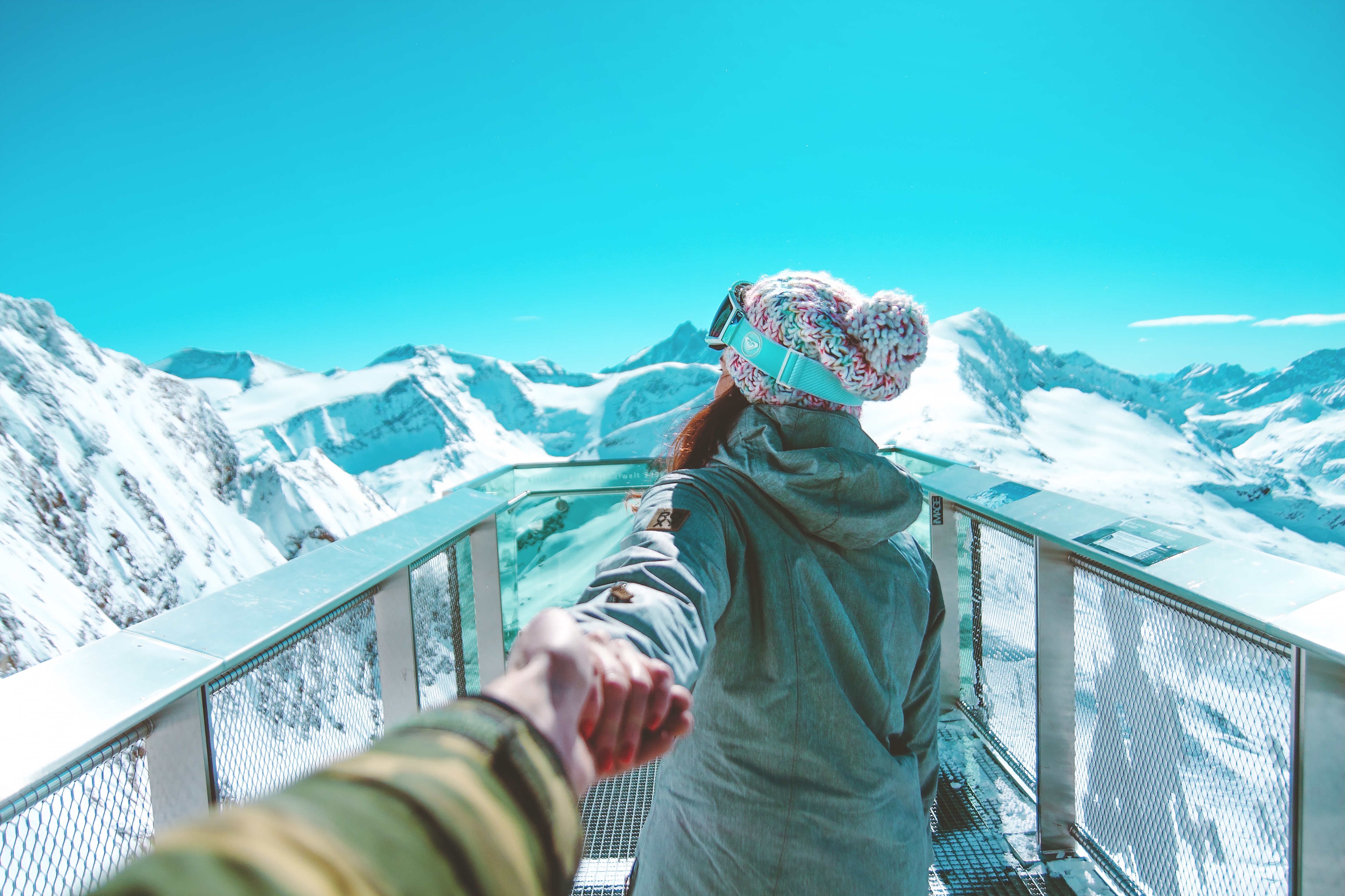 Couple holding hands on a snowy mountain observation deck HD Wallpaper