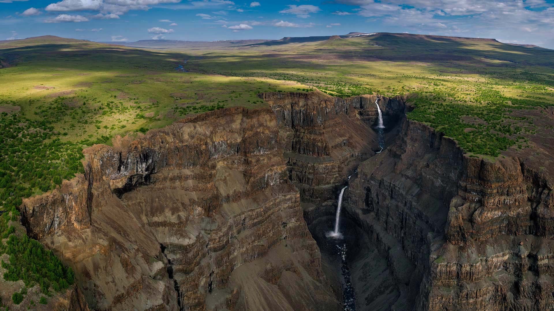 Waterfalls in a vast canyon under a cloudy sky HD Wallpaper