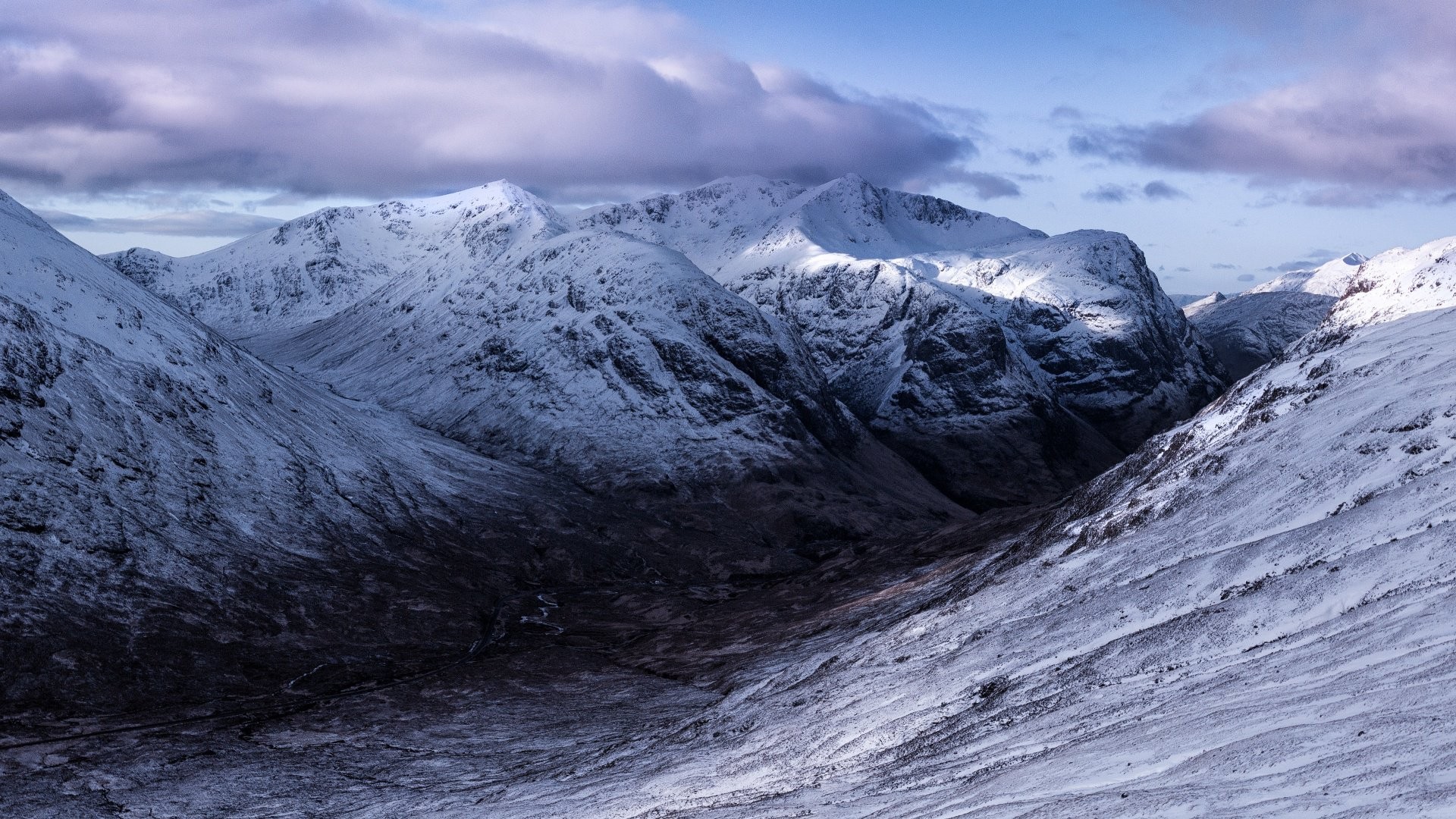 Snow-covered mountains under a cloudy sky HD Wallpaper