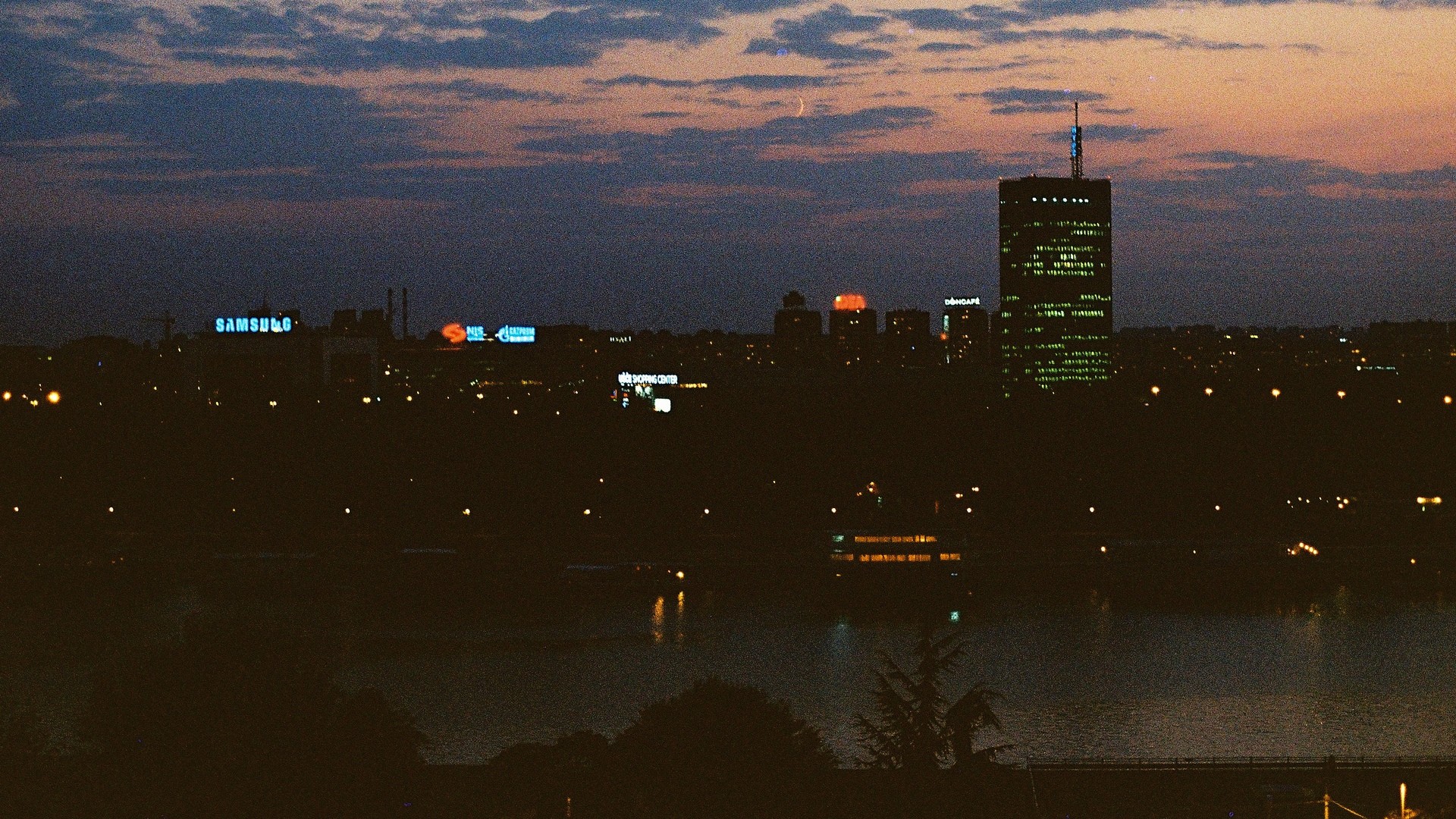 Cityscape at dusk with Samsung sign and moon HD Wallpaper