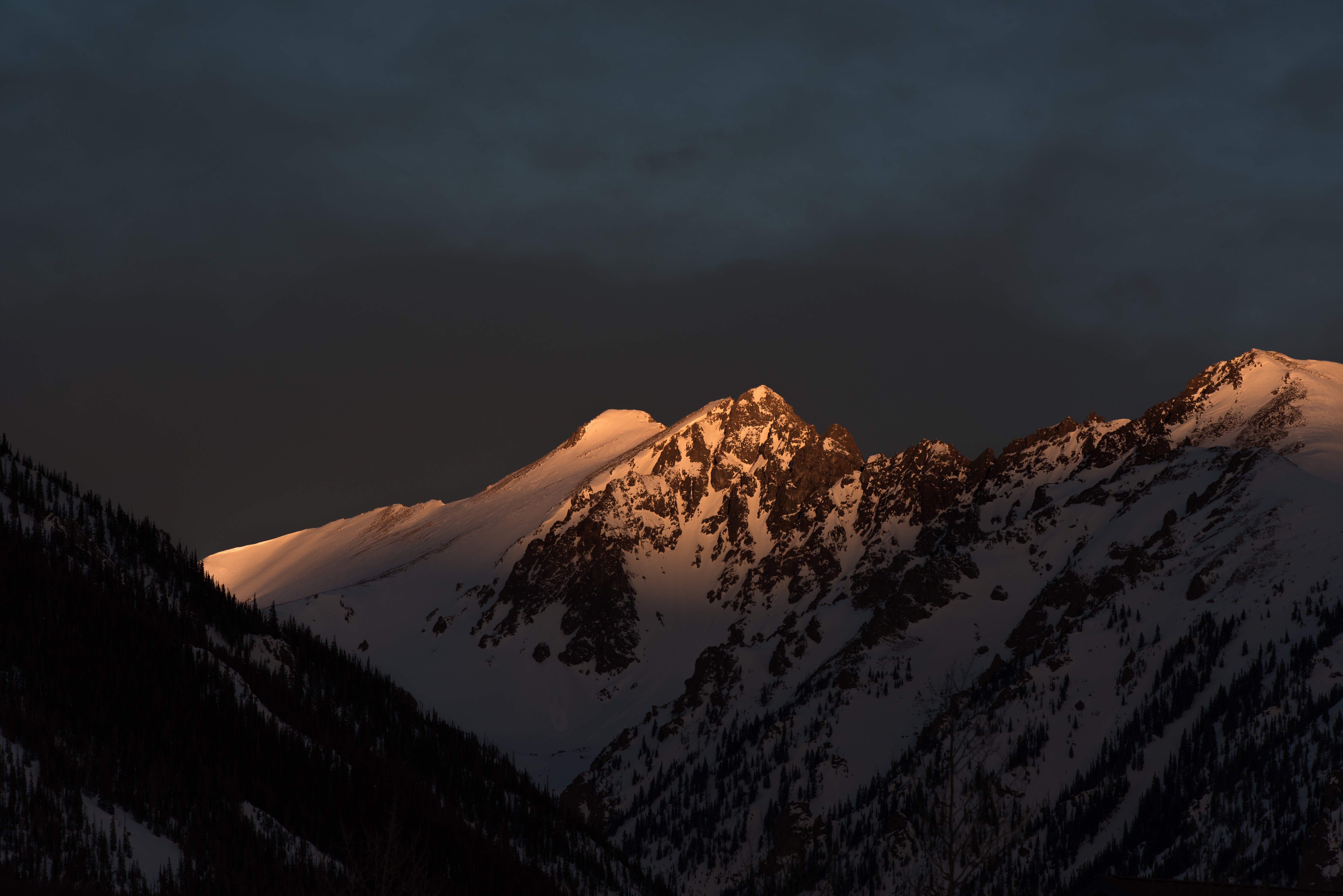 Snow-covered mountains illuminated by golden hour light HD Wallpaper