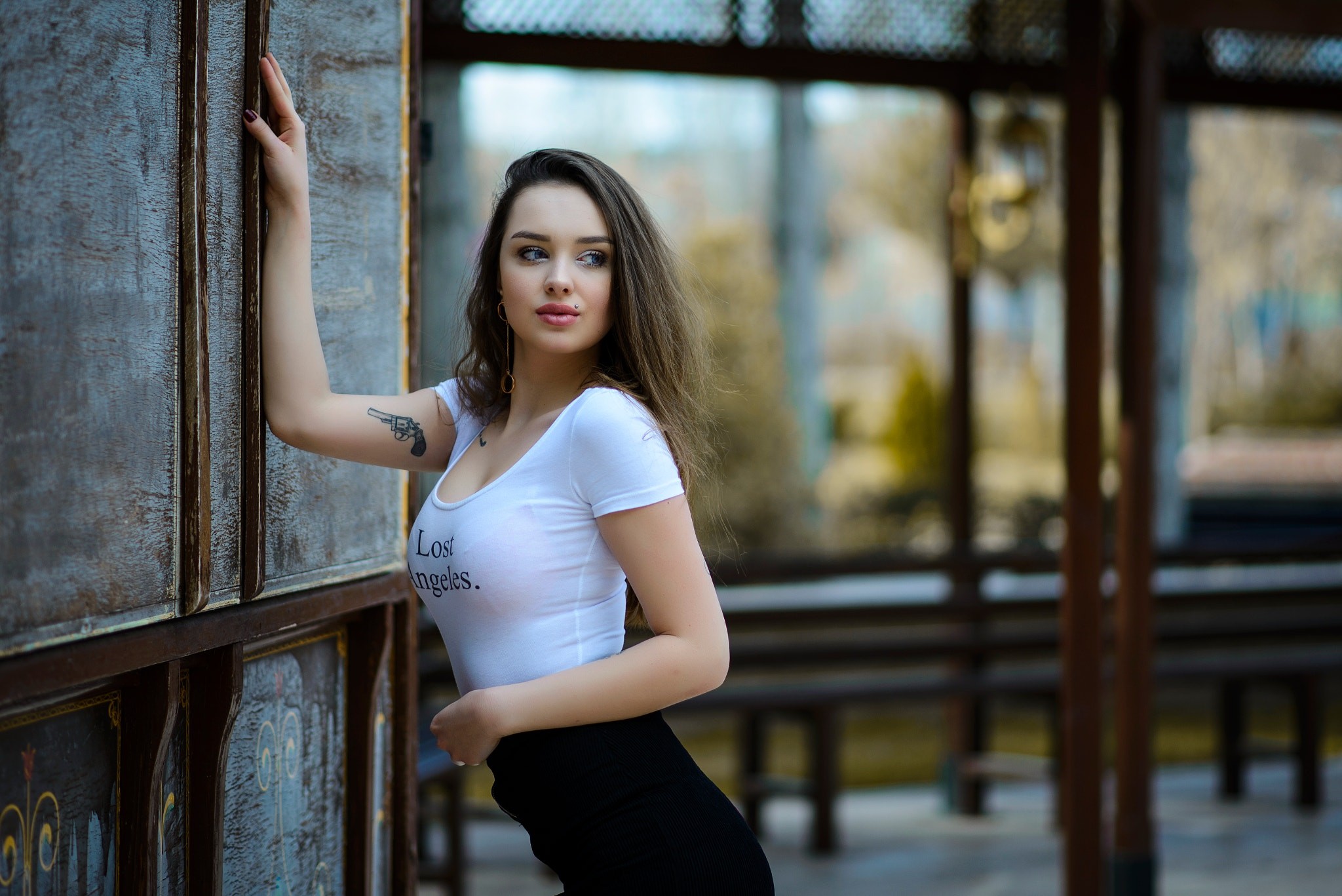 Woman with tattoo leaning against a wooden structure HD Wallpaper