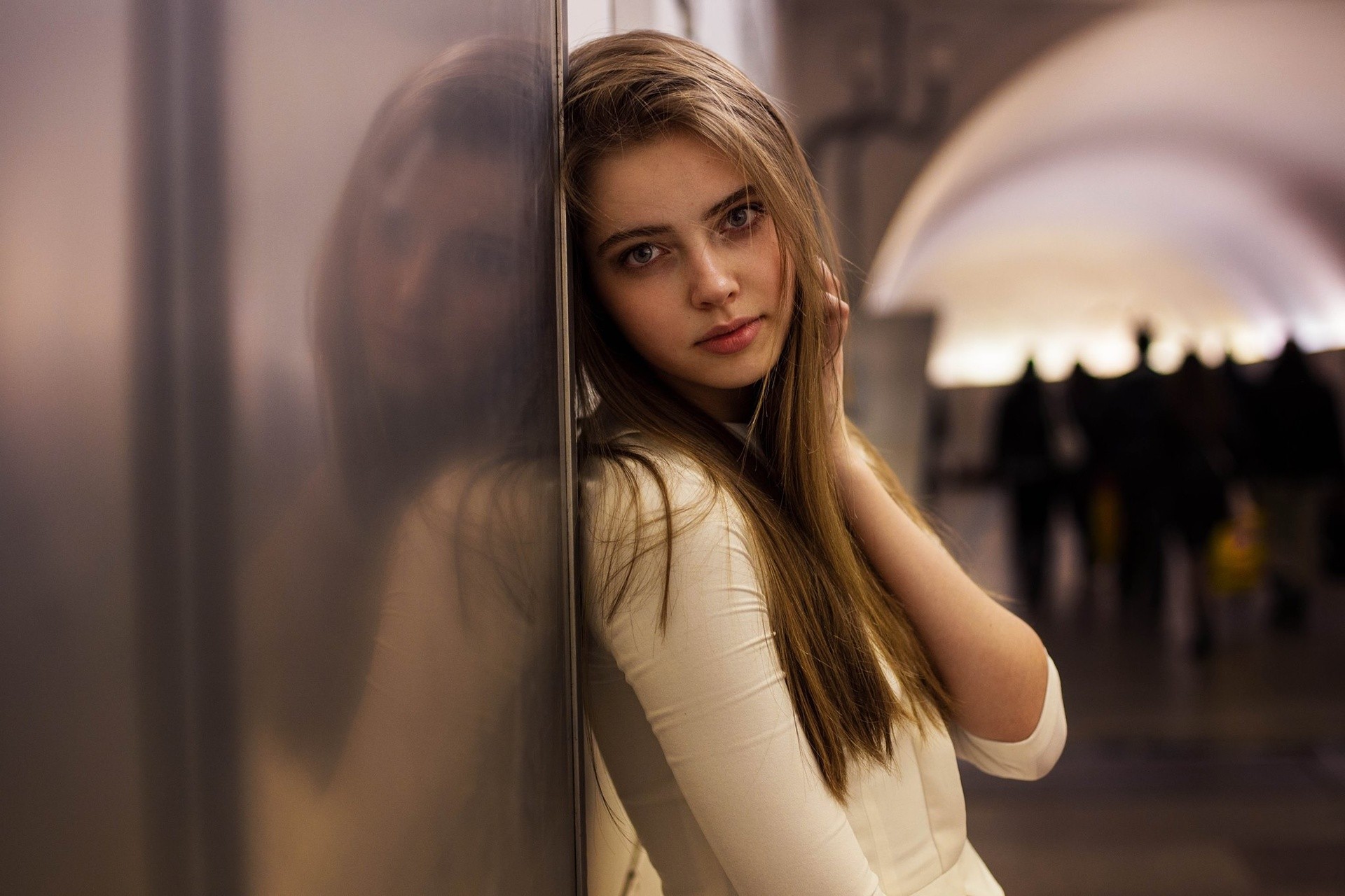 Young woman with long brown hair leaning against a wall HD Wallpaper