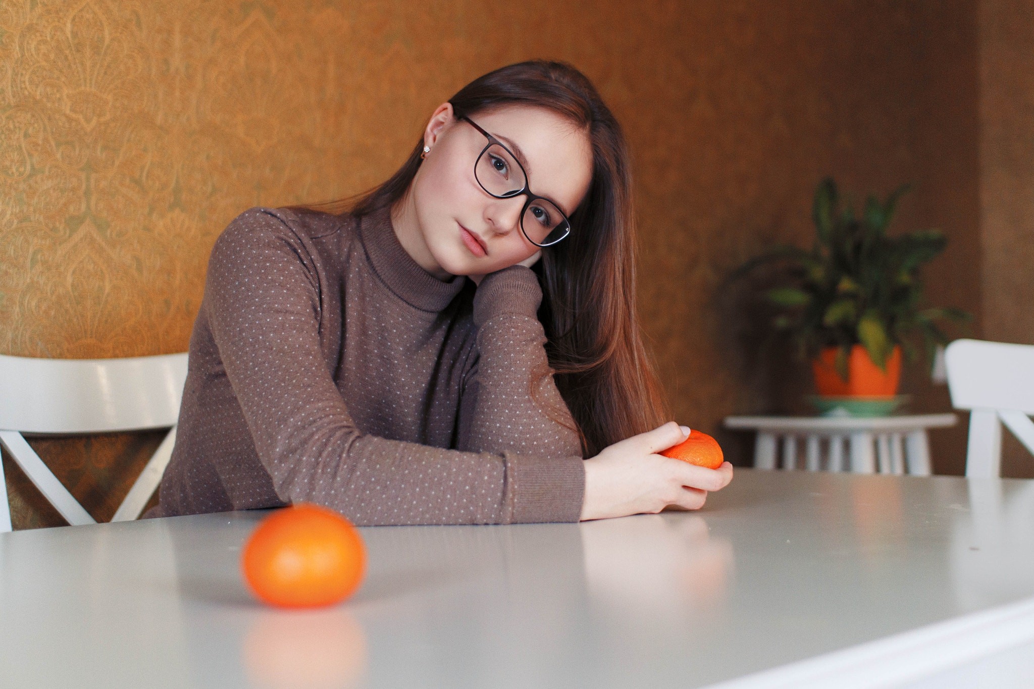 Young woman with glasses sitting at a table with oranges HD Wallpaper