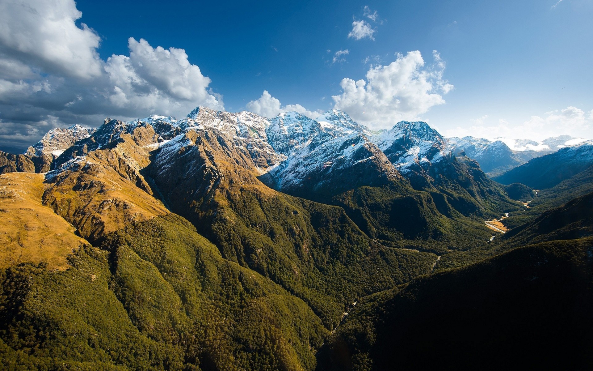 Snow-capped mountains and green valleys under a blue sky HD Wallpaper