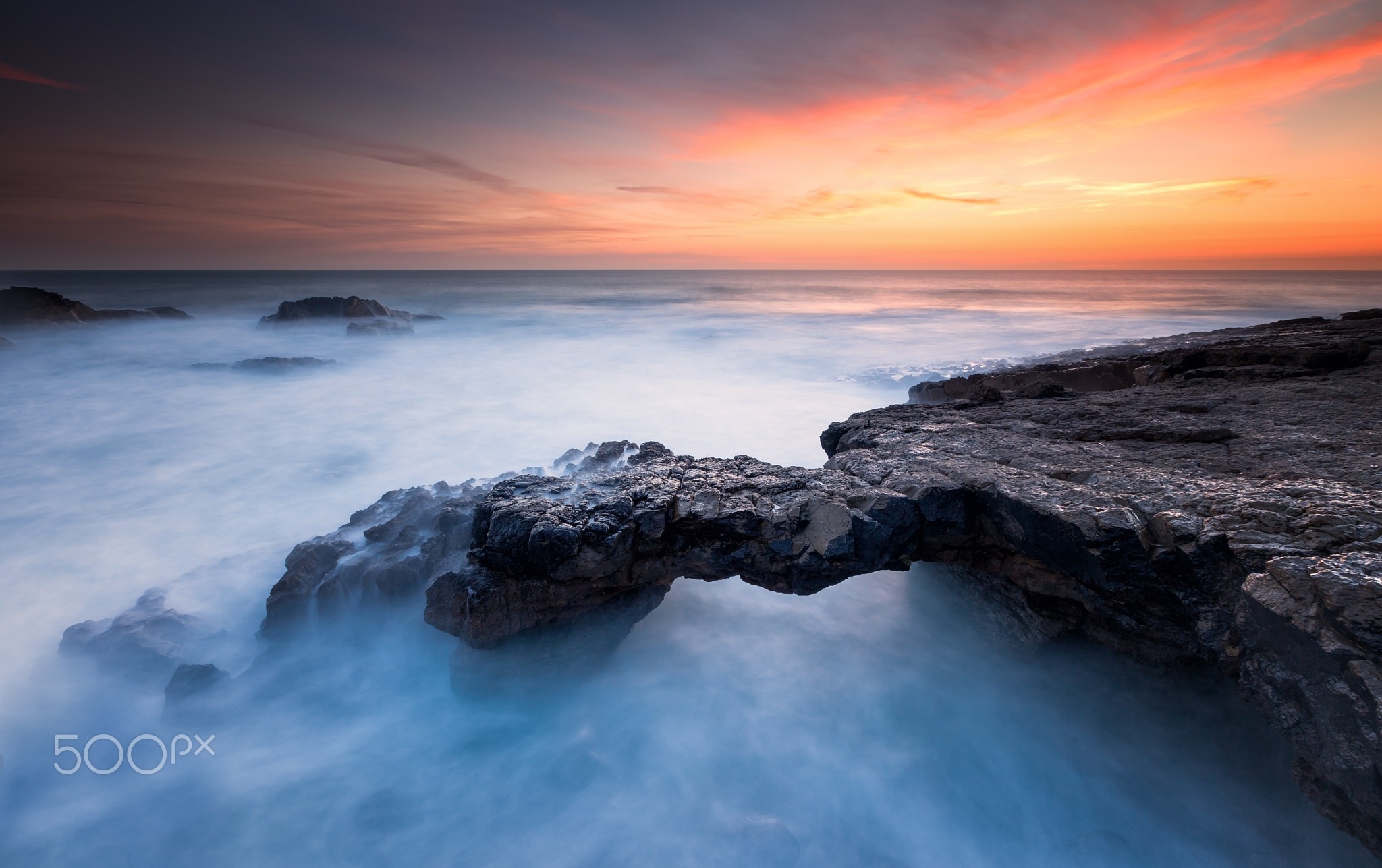 Sea arch at sunset with misty water HD Wallpaper