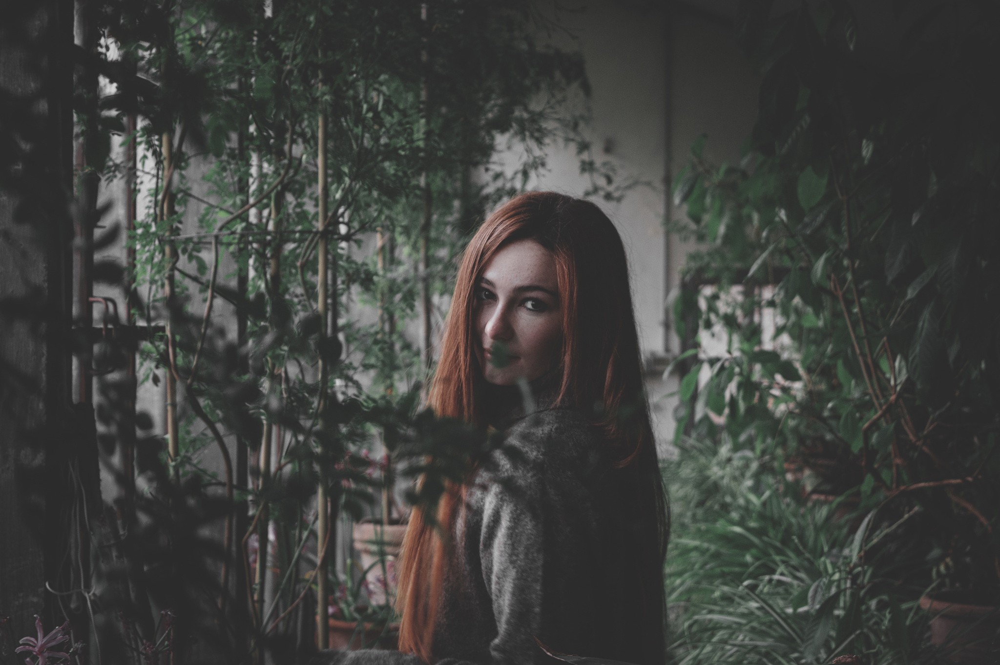 Redhead woman looking over shoulder in garden HD Wallpaper