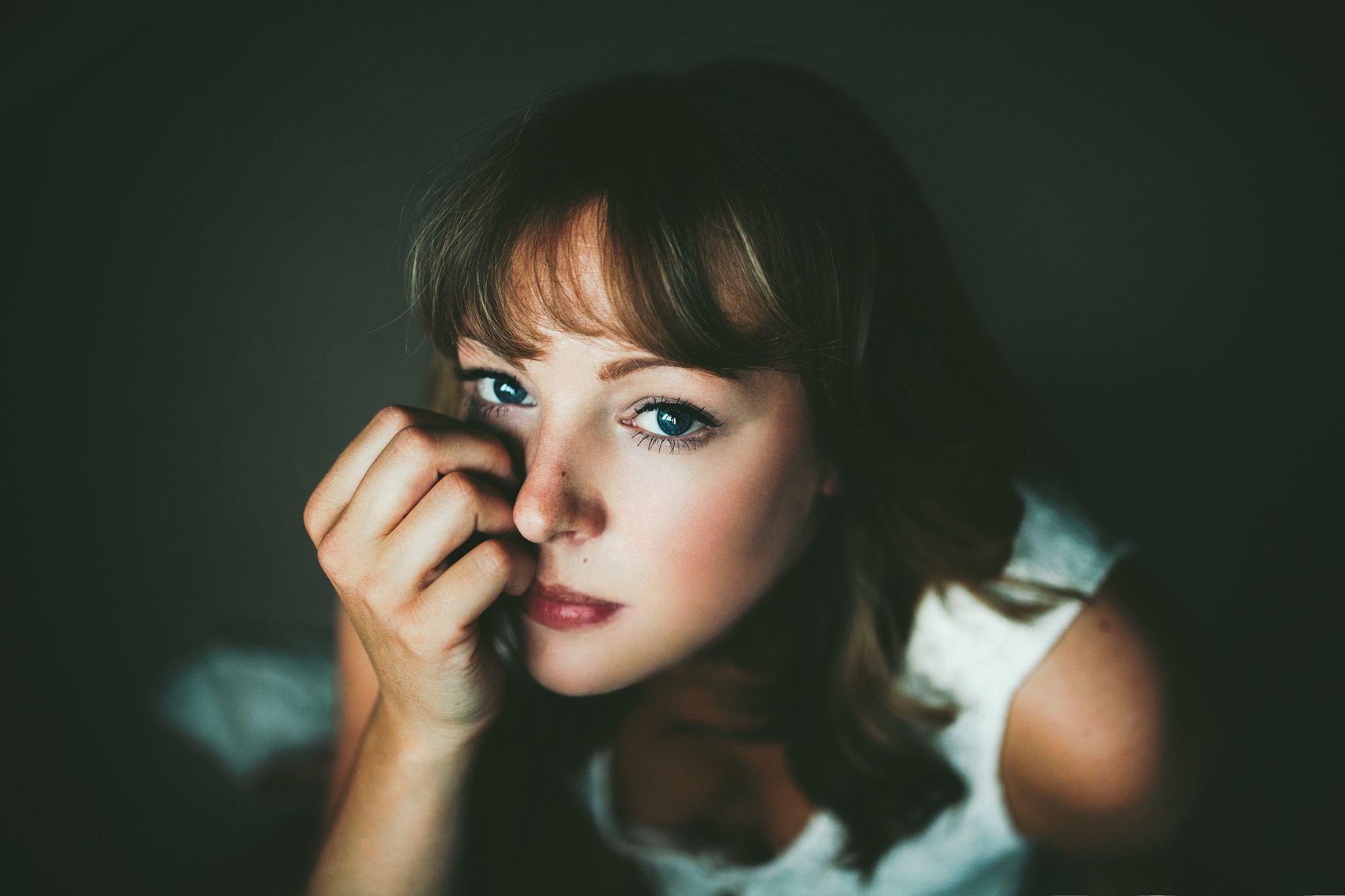 Woman with hand on face looking at viewer HD Wallpaper
