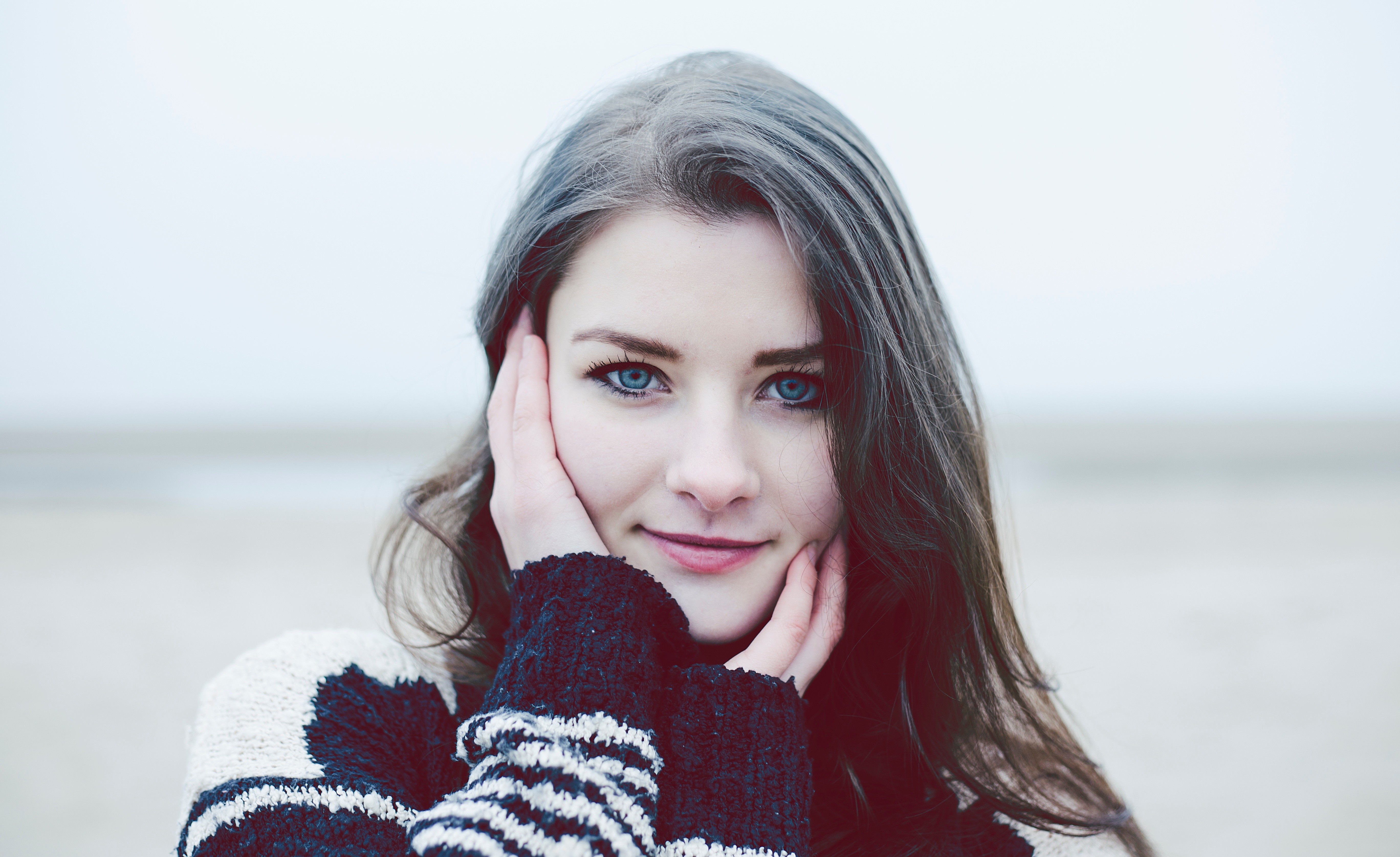 Woman with blue eyes wearing a sweater outdoors HD Wallpaper