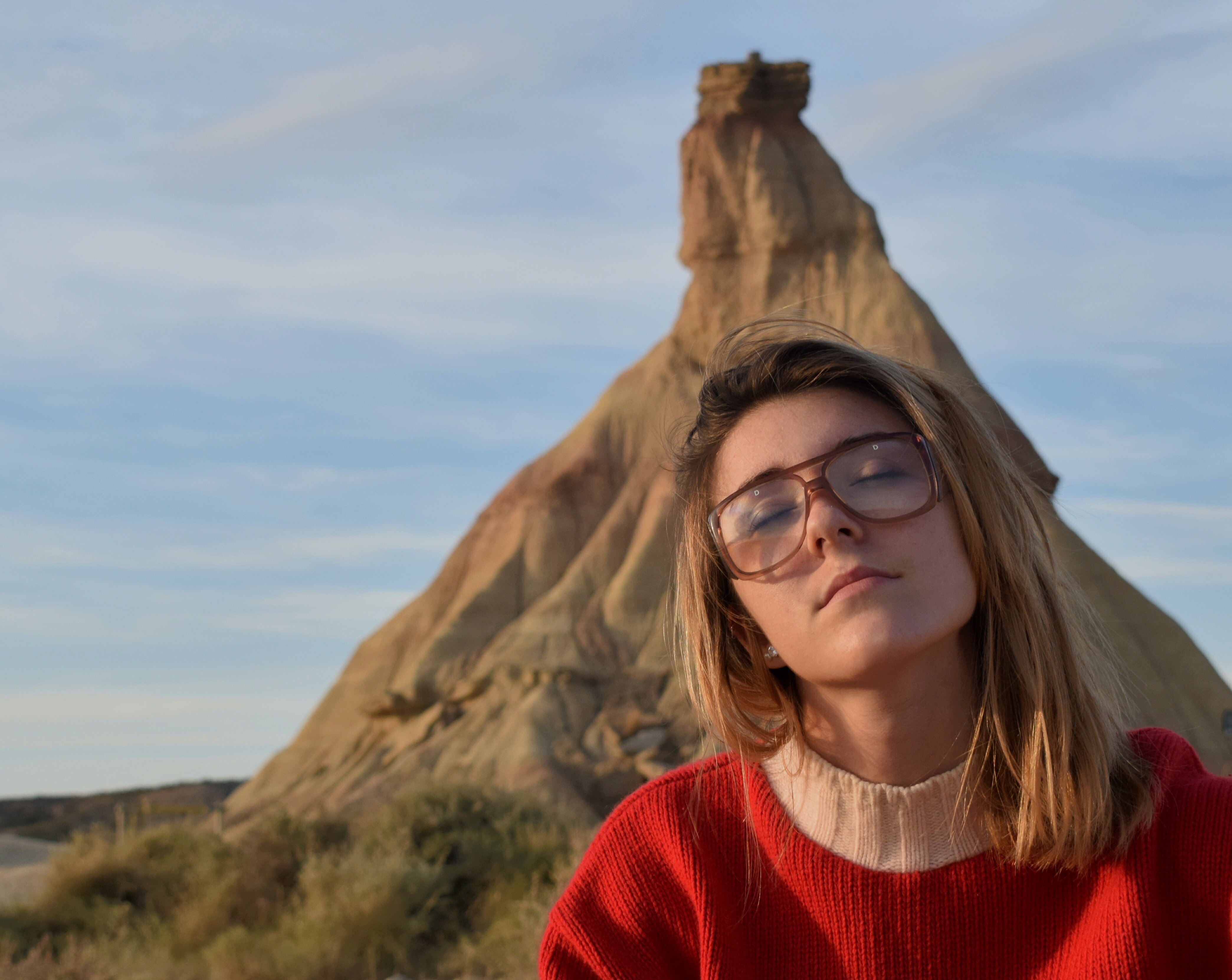 Woman with glasses in a red sweater in a desert landscape HD Wallpaper