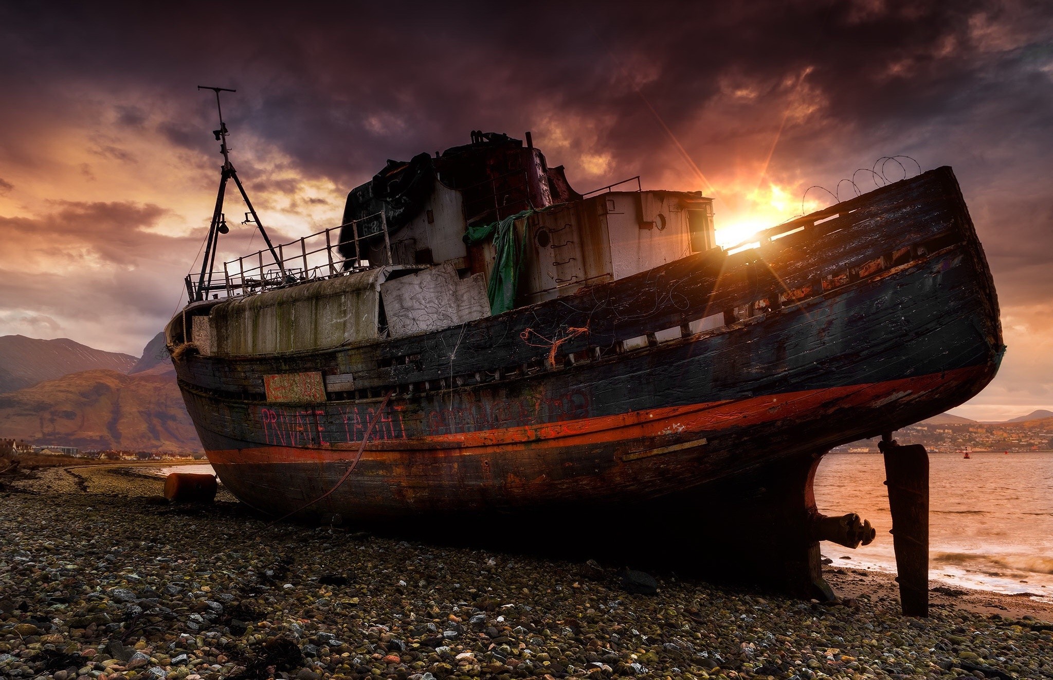 Abandoned shipwreck on a rocky shore at sunset HD Wallpaper