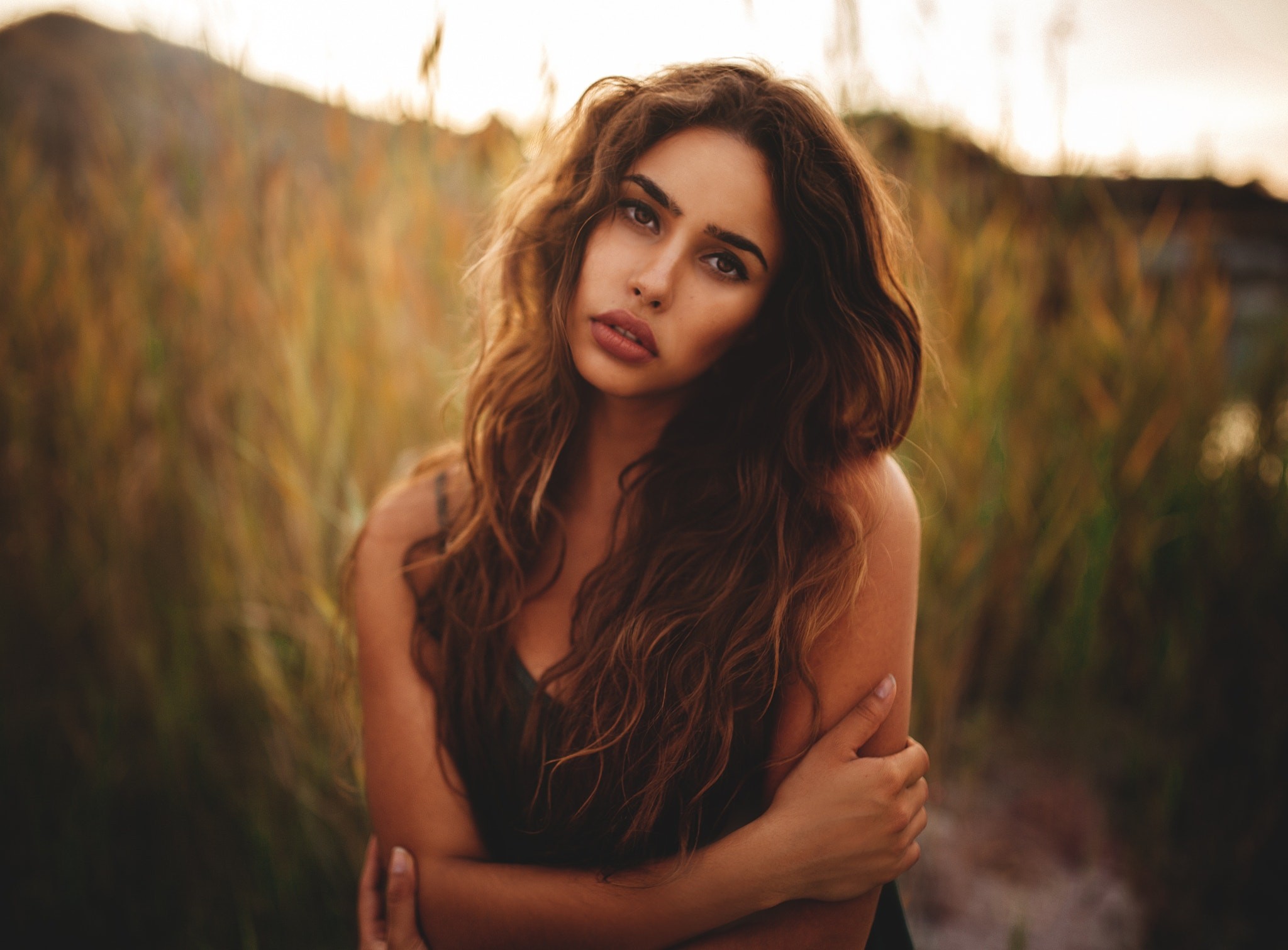 Woman with long wavy hair in a field HD Wallpaper