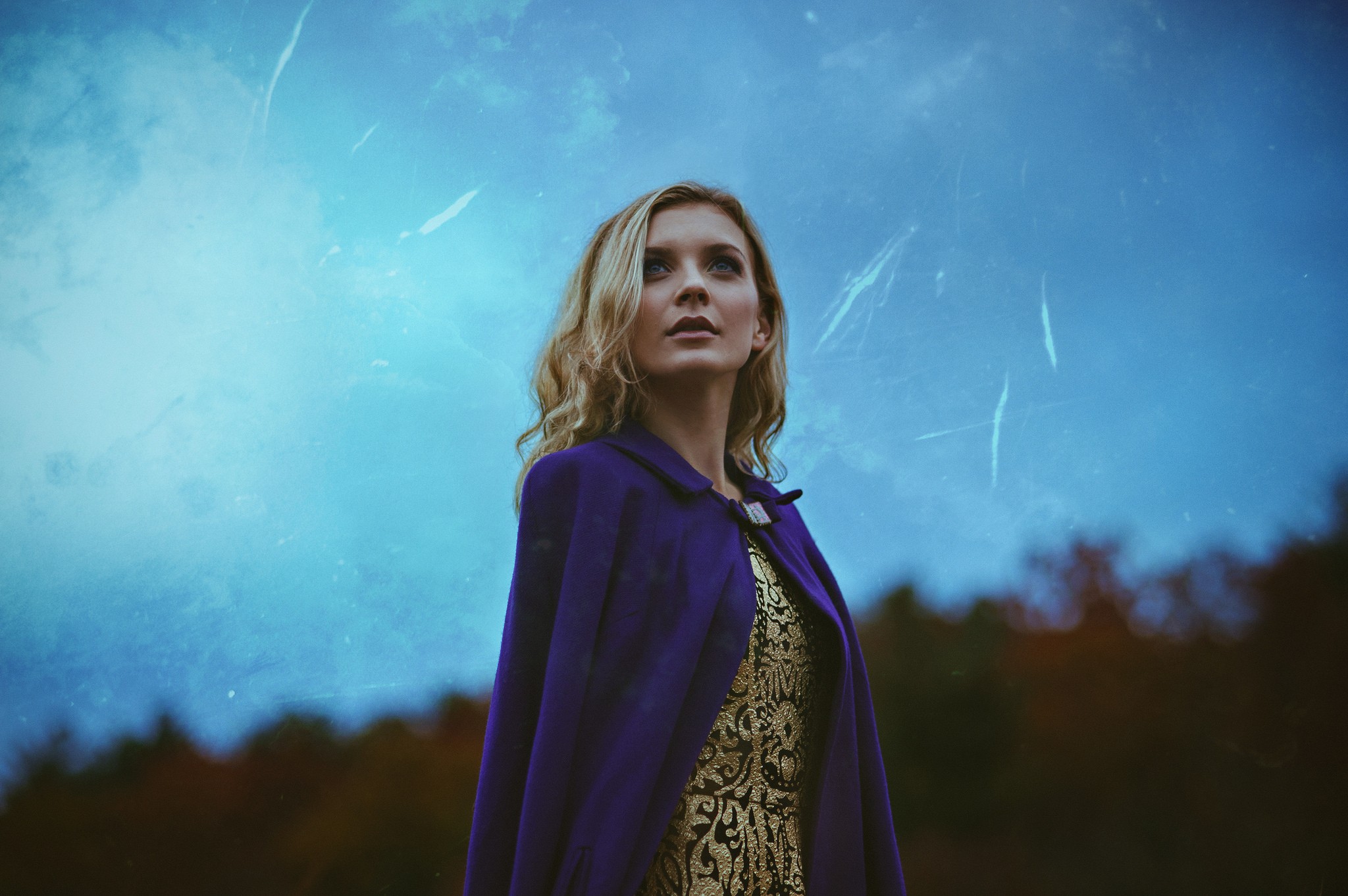 Woman in purple cloak and gold dress looking up HD Wallpaper