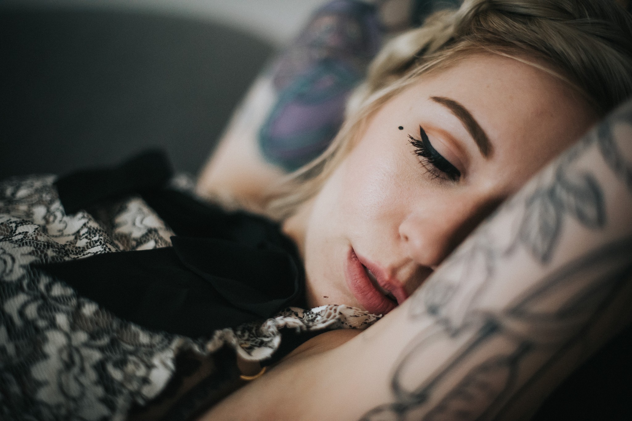 Woman with tattoos lying down with eyes closed HD Wallpaper