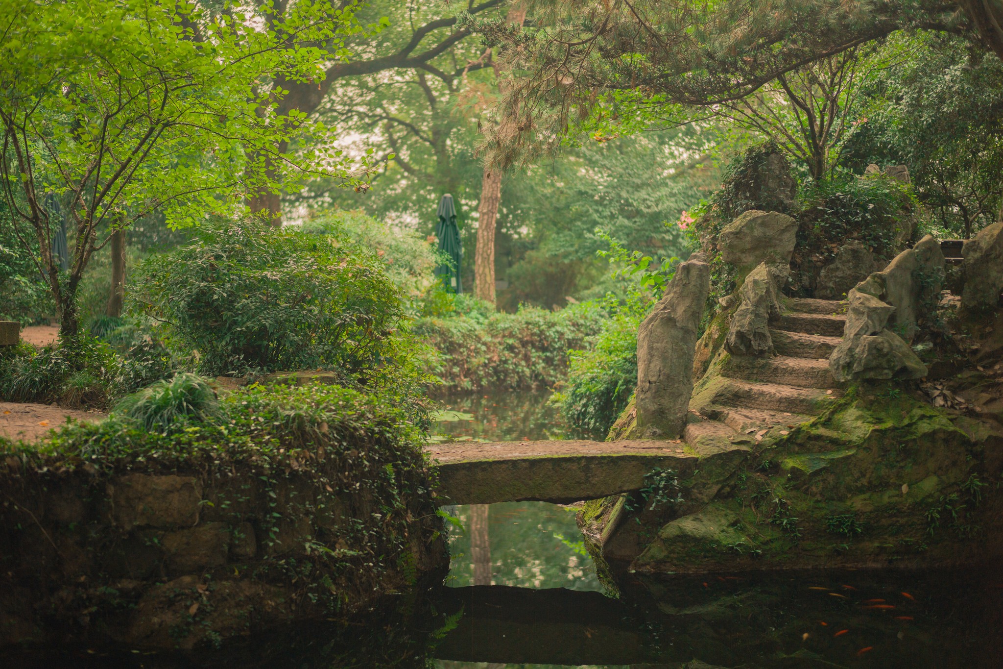 Stone bridge over water in a park with trees and rocks HD Wallpaper