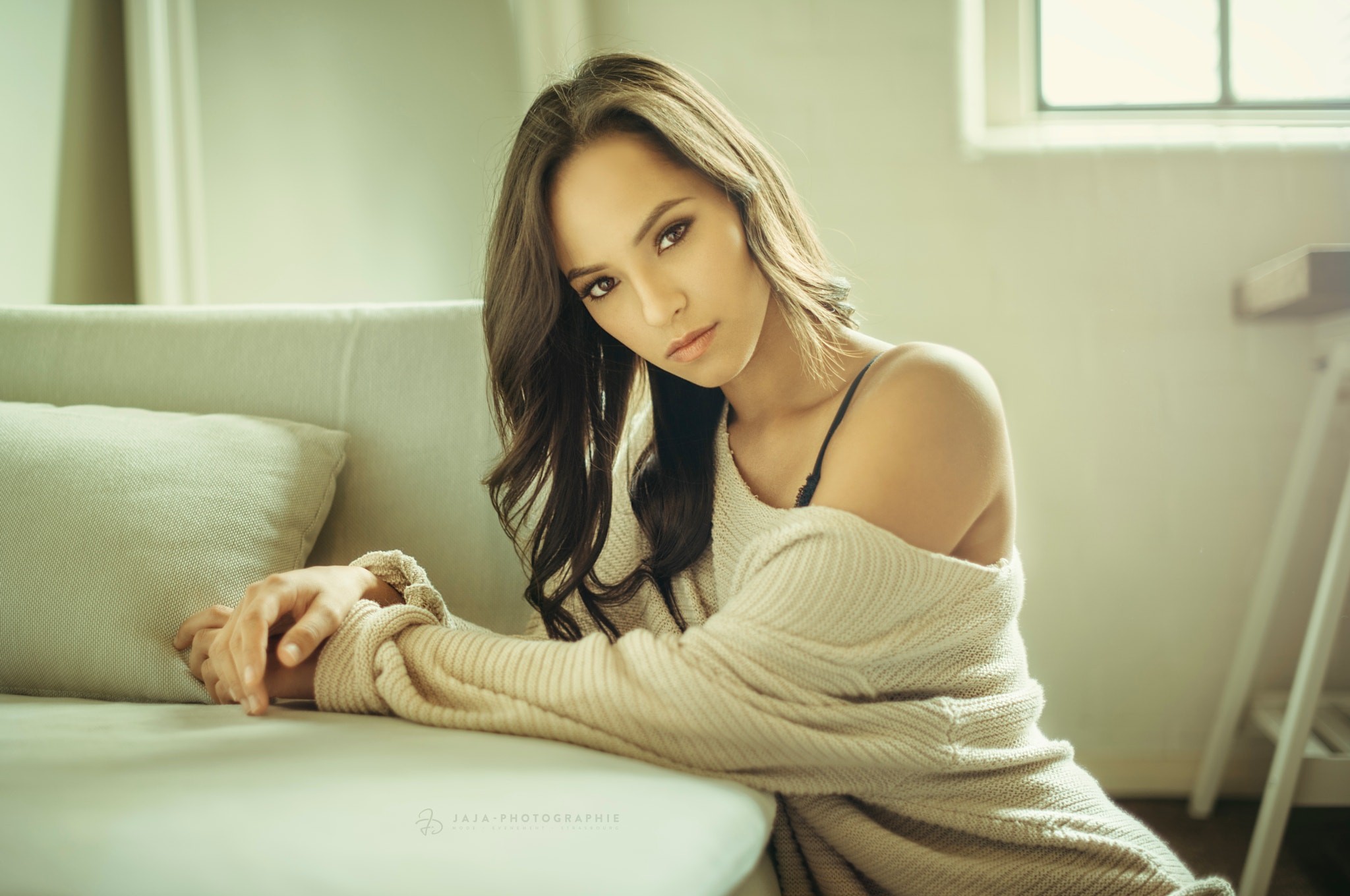 Woman in a sweater sitting on a couch HD Wallpaper