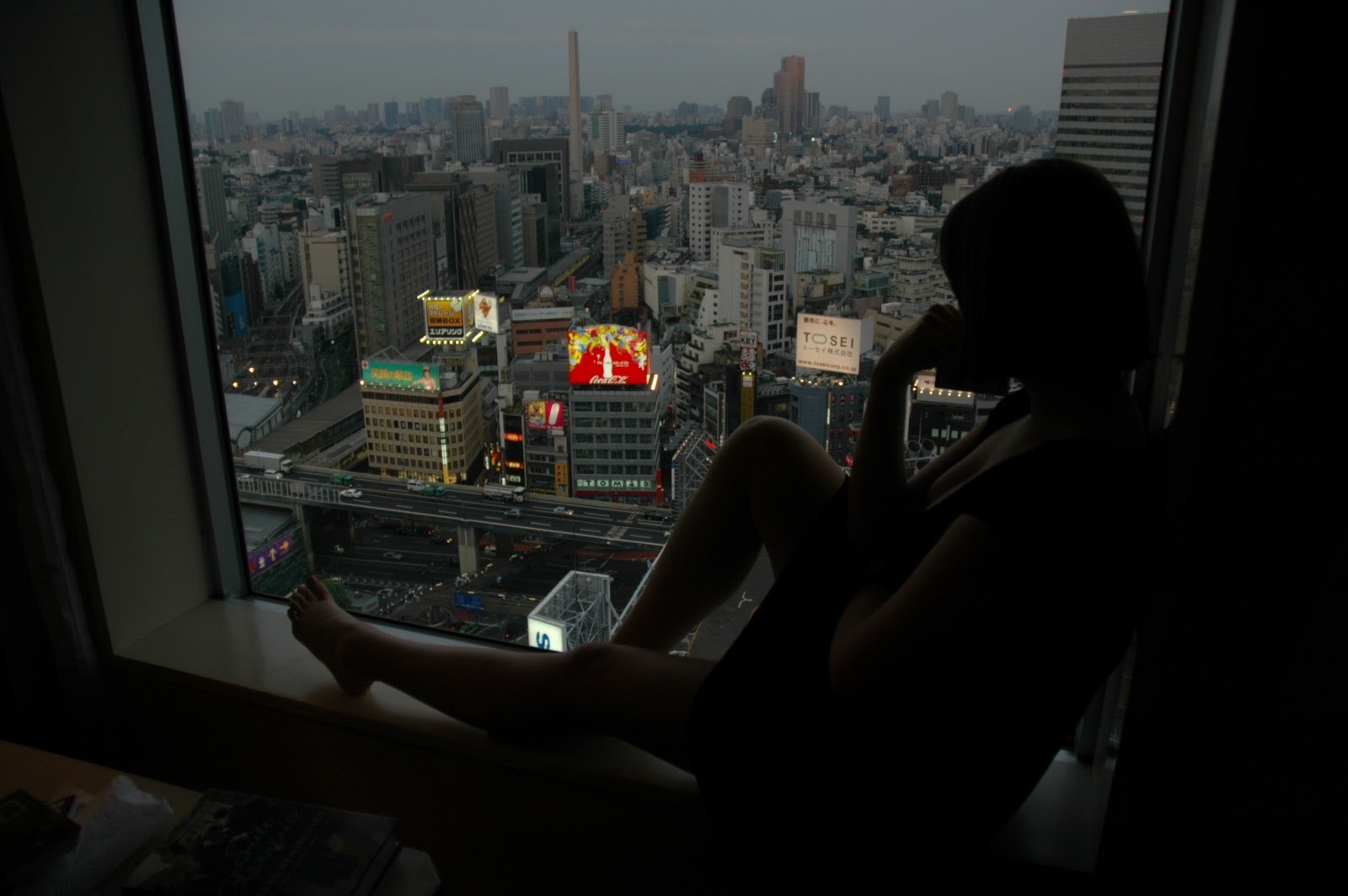 Woman looking out window at Tokyo cityscape at dusk HD Wallpaper