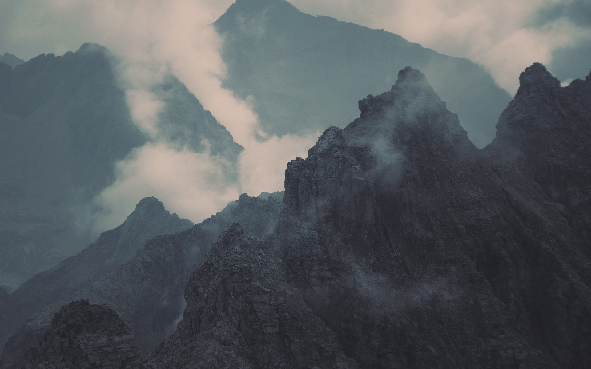 Misty mountain peaks shrouded in clouds HD Wallpaper