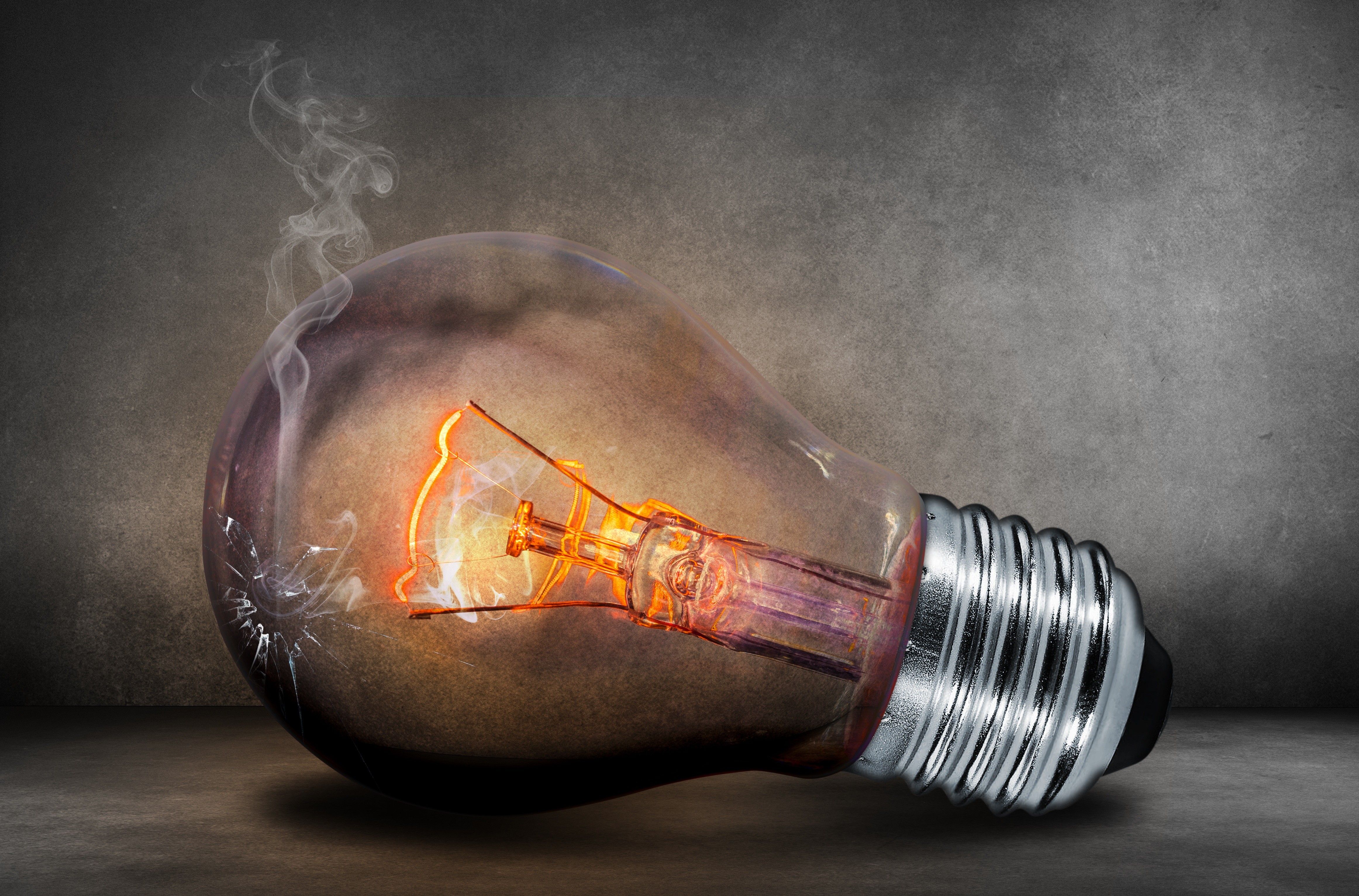 Broken light bulb with glowing filament and smoke HD Wallpaper