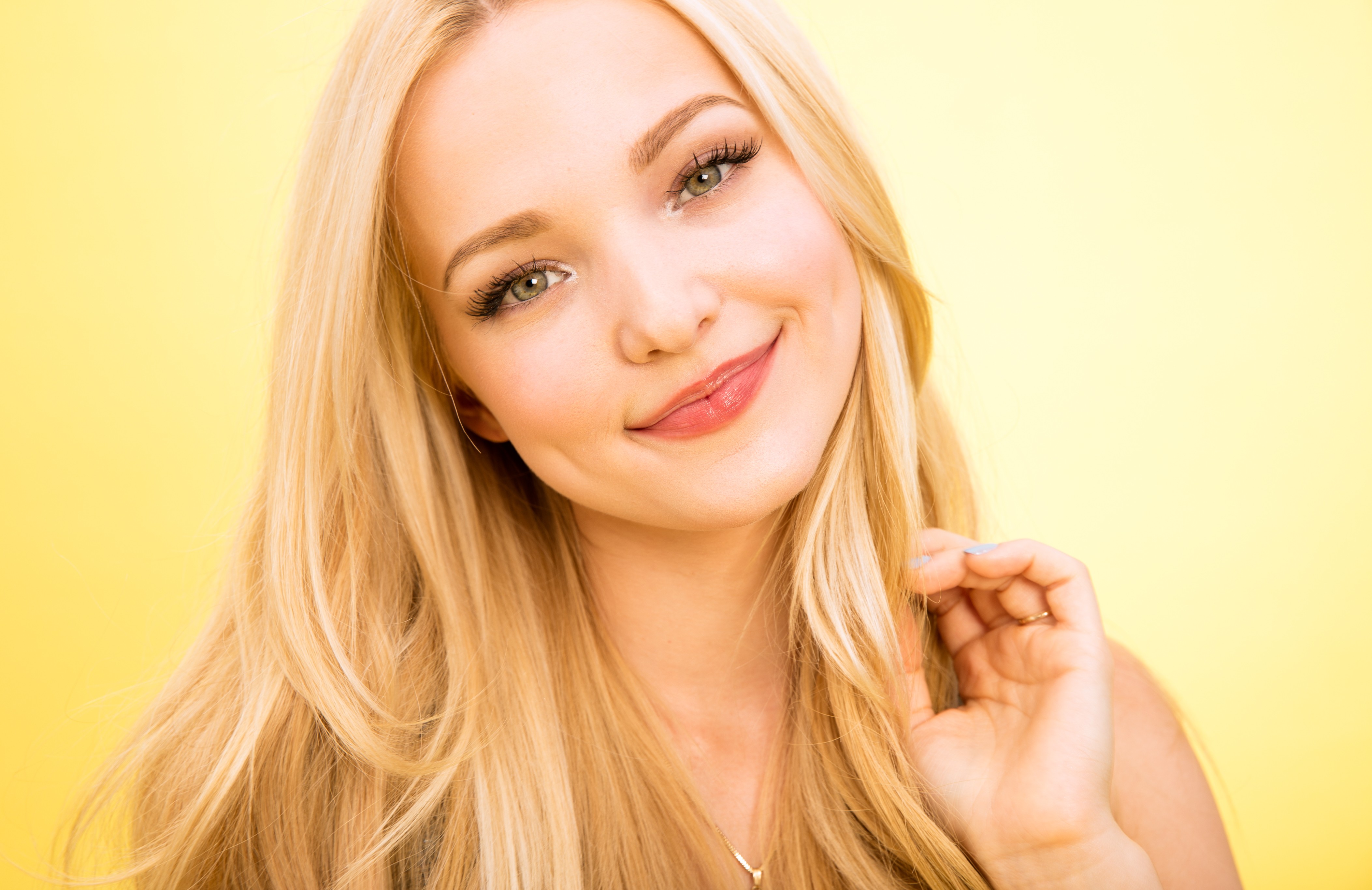 Dove Cameron smiling against a yellow background HD Wallpaper