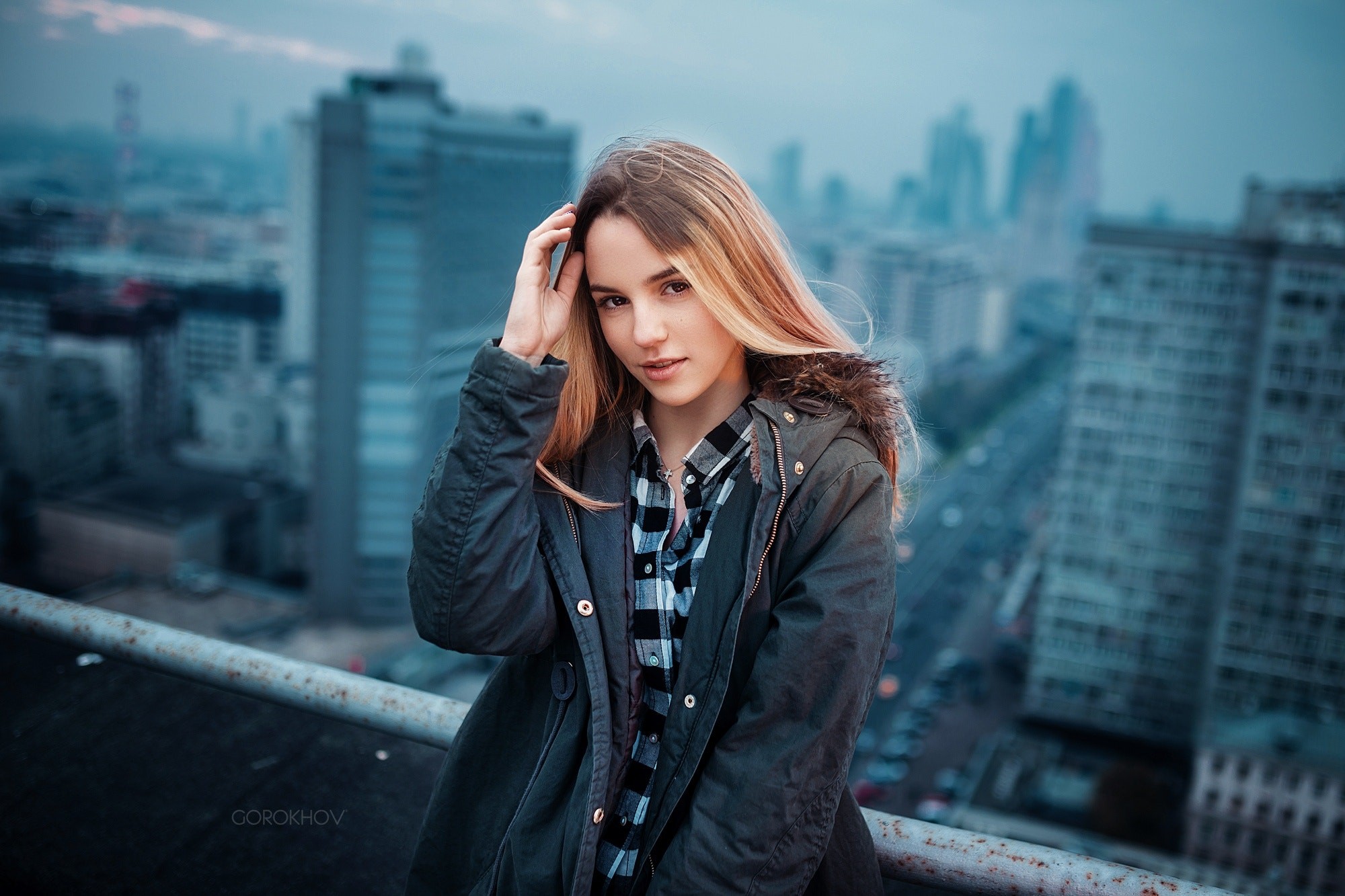 Woman in jacket and shirt on rooftop overlooking cityscape HD Wallpaper