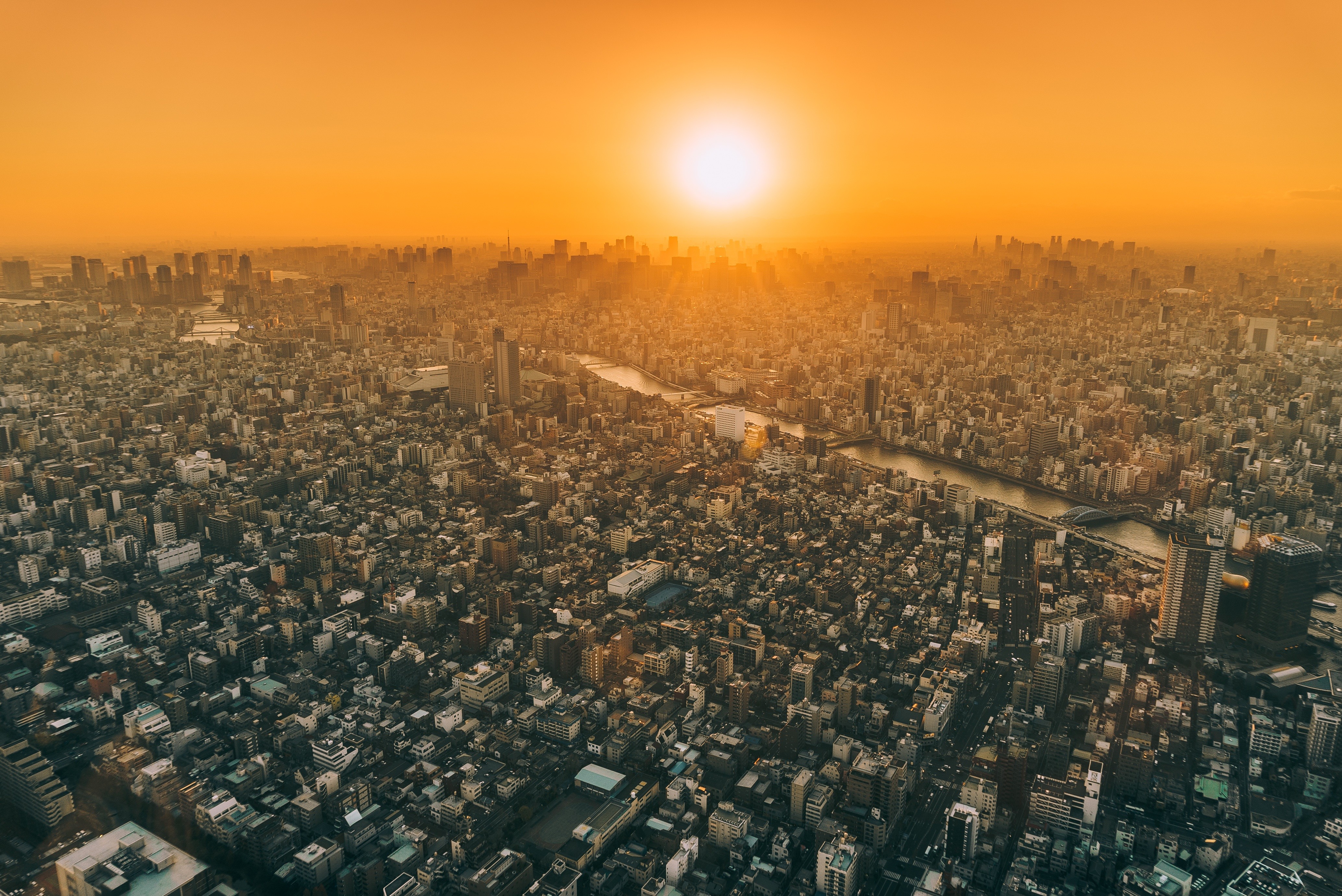 Aerial view of a city at sunset with a river HD Wallpaper