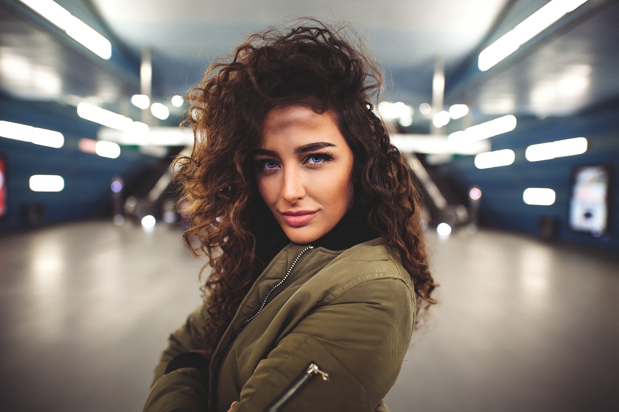 Woman with curly hair in a subway station HD Wallpaper