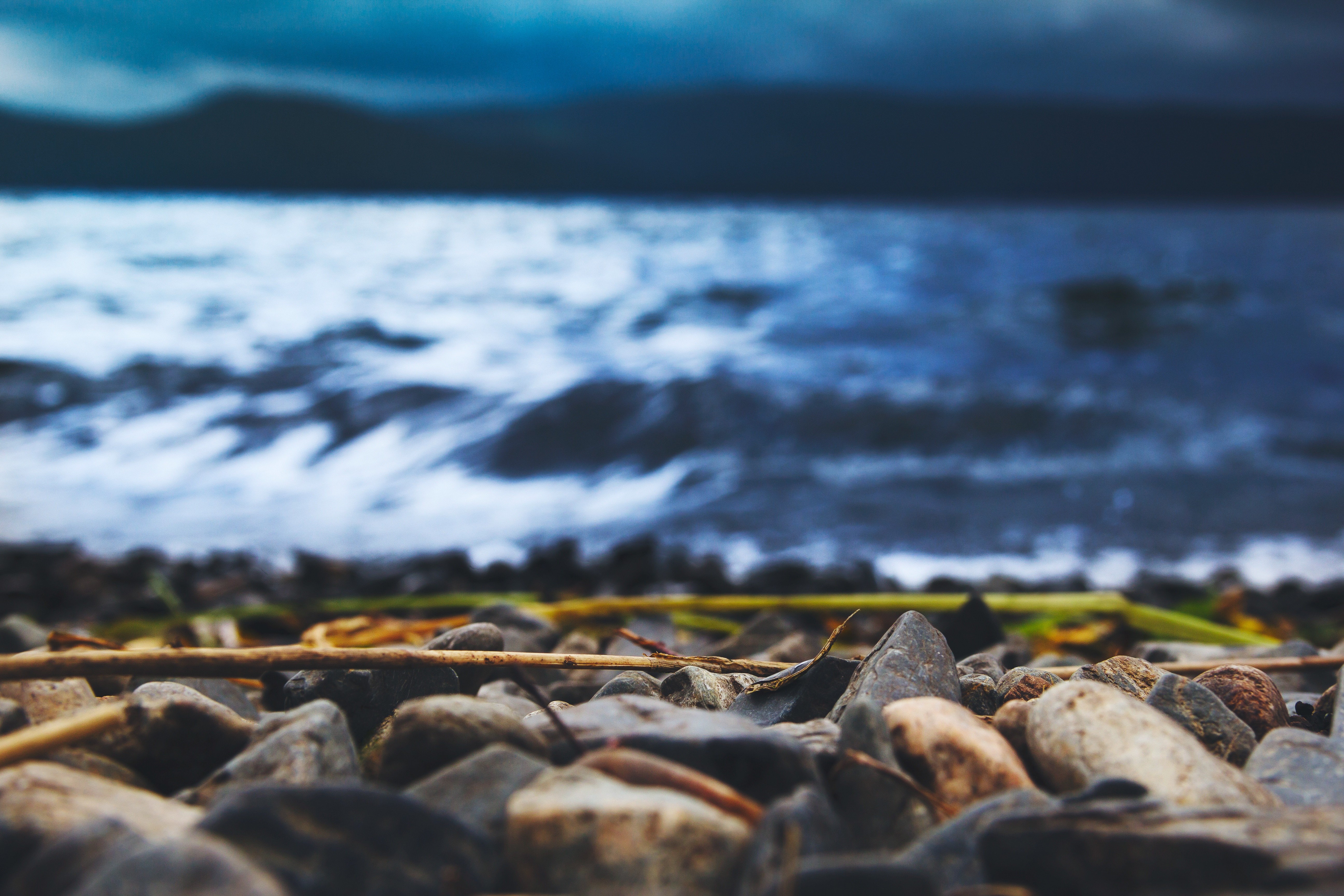 Rocky shore with choppy water and dark sky HD Wallpaper