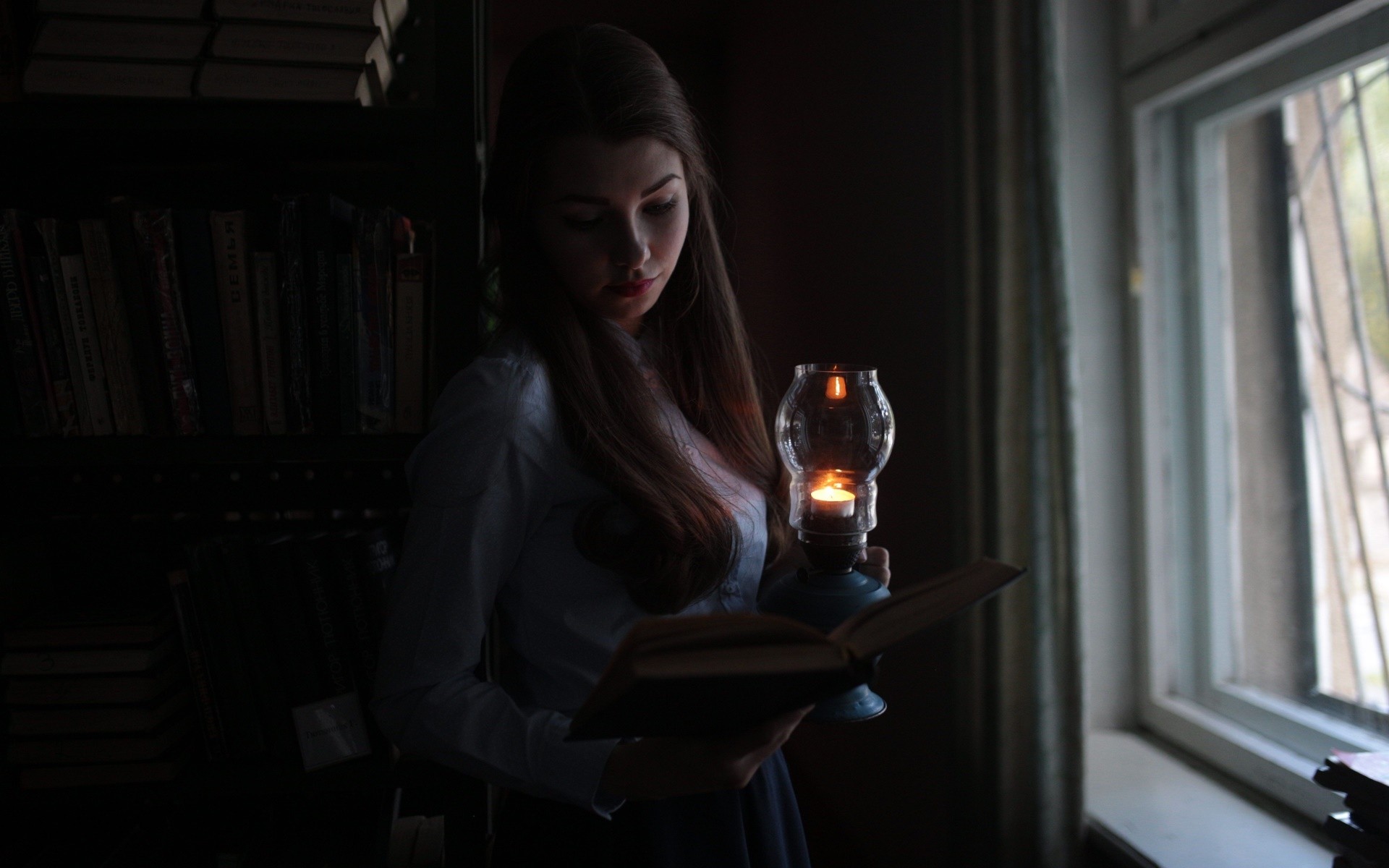 Woman reading a book by lantern light near a window HD Wallpaper