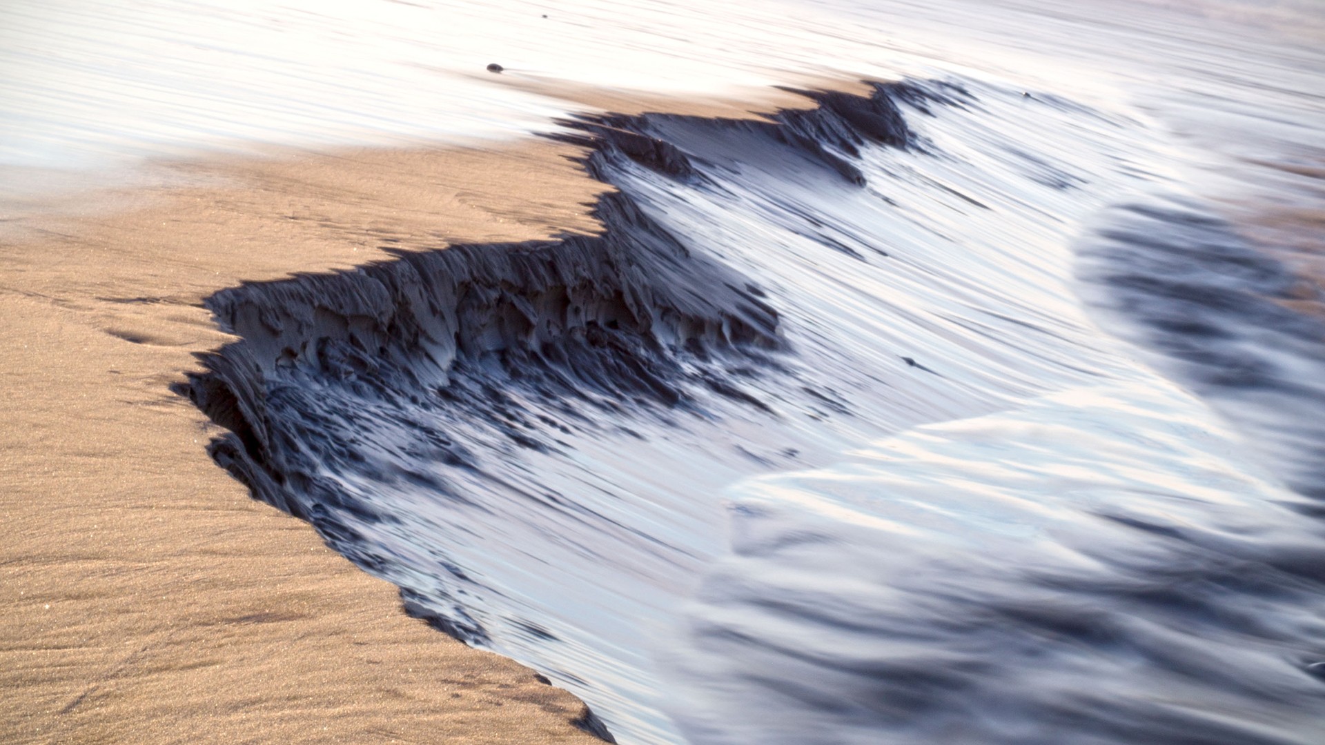 Long exposure of waves crashing on a sandy shore HD Wallpaper
