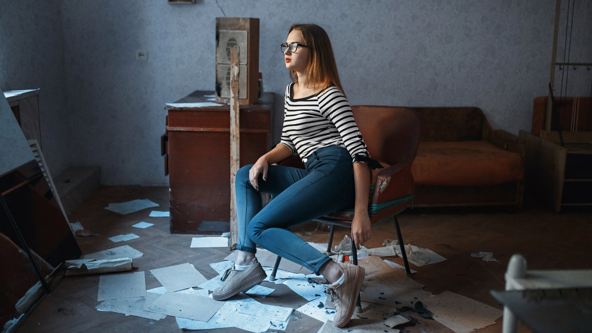 Woman with glasses sitting in a chair in a room HD Wallpaper
