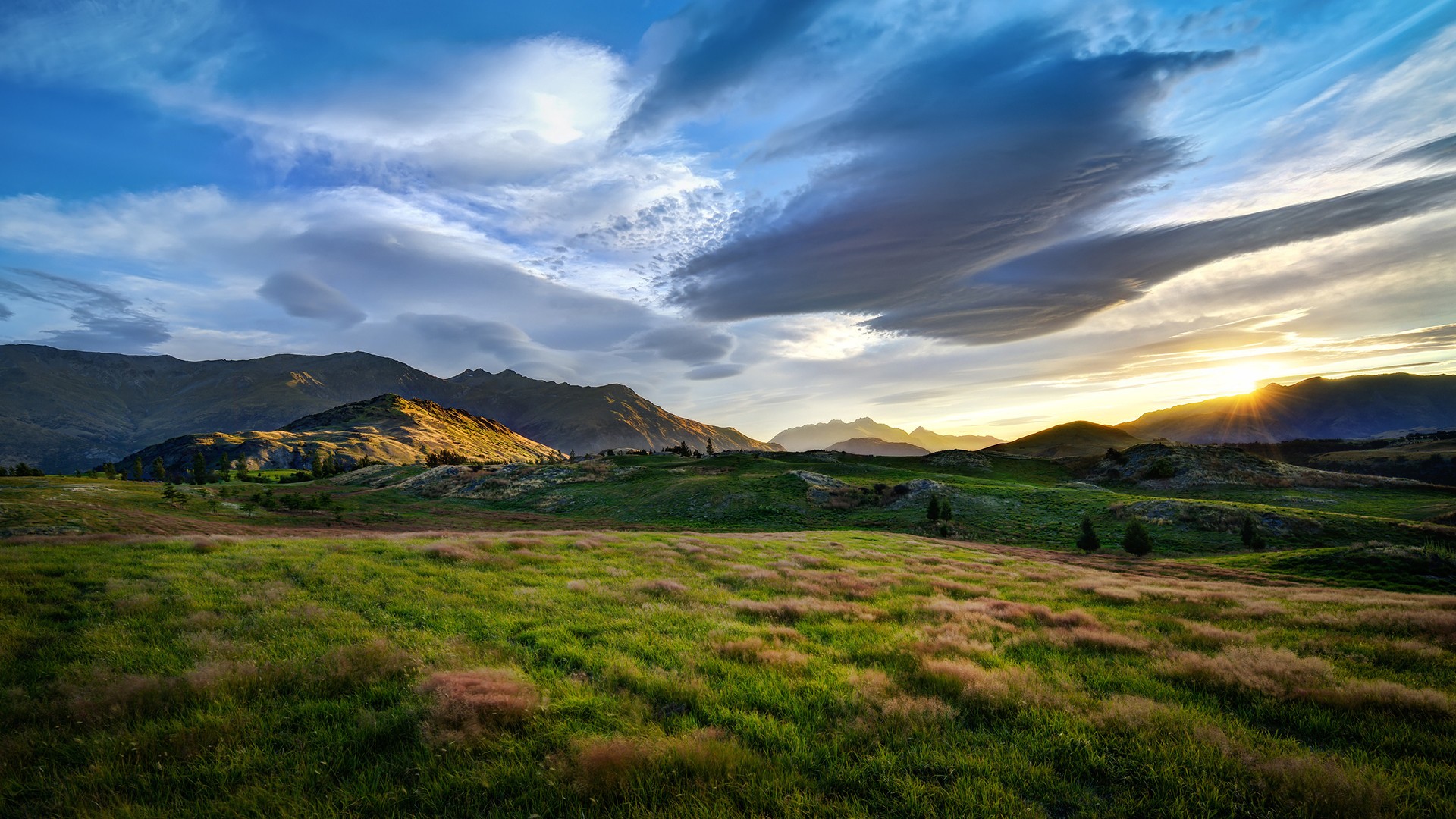 Rolling green hills and mountains at sunset HD Wallpaper