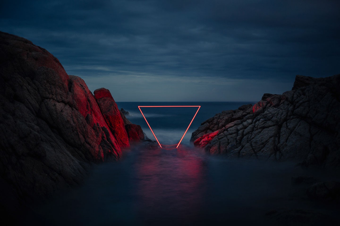 Neon triangle over water between rocks at dusk HD Wallpaper