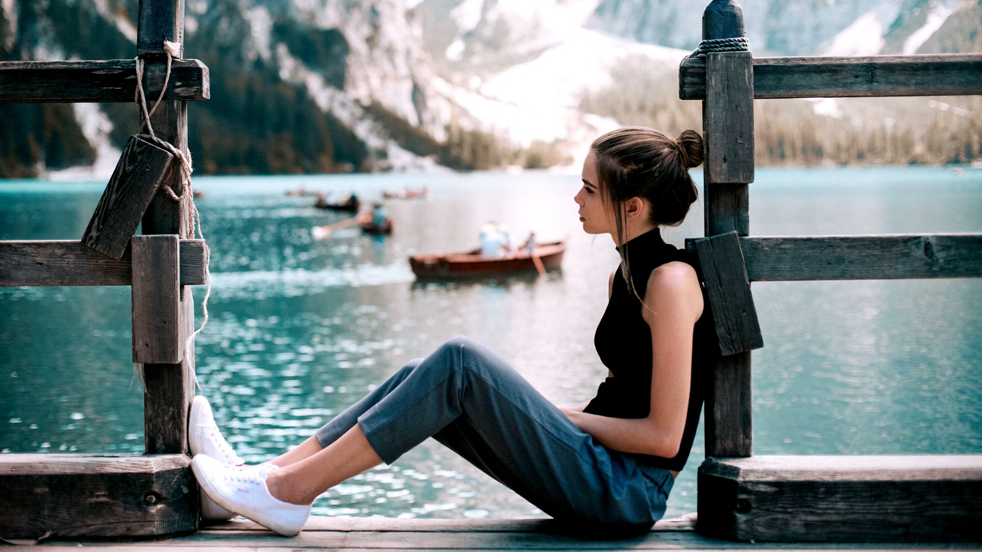 Woman sitting on a wooden dock by a lake HD Wallpaper