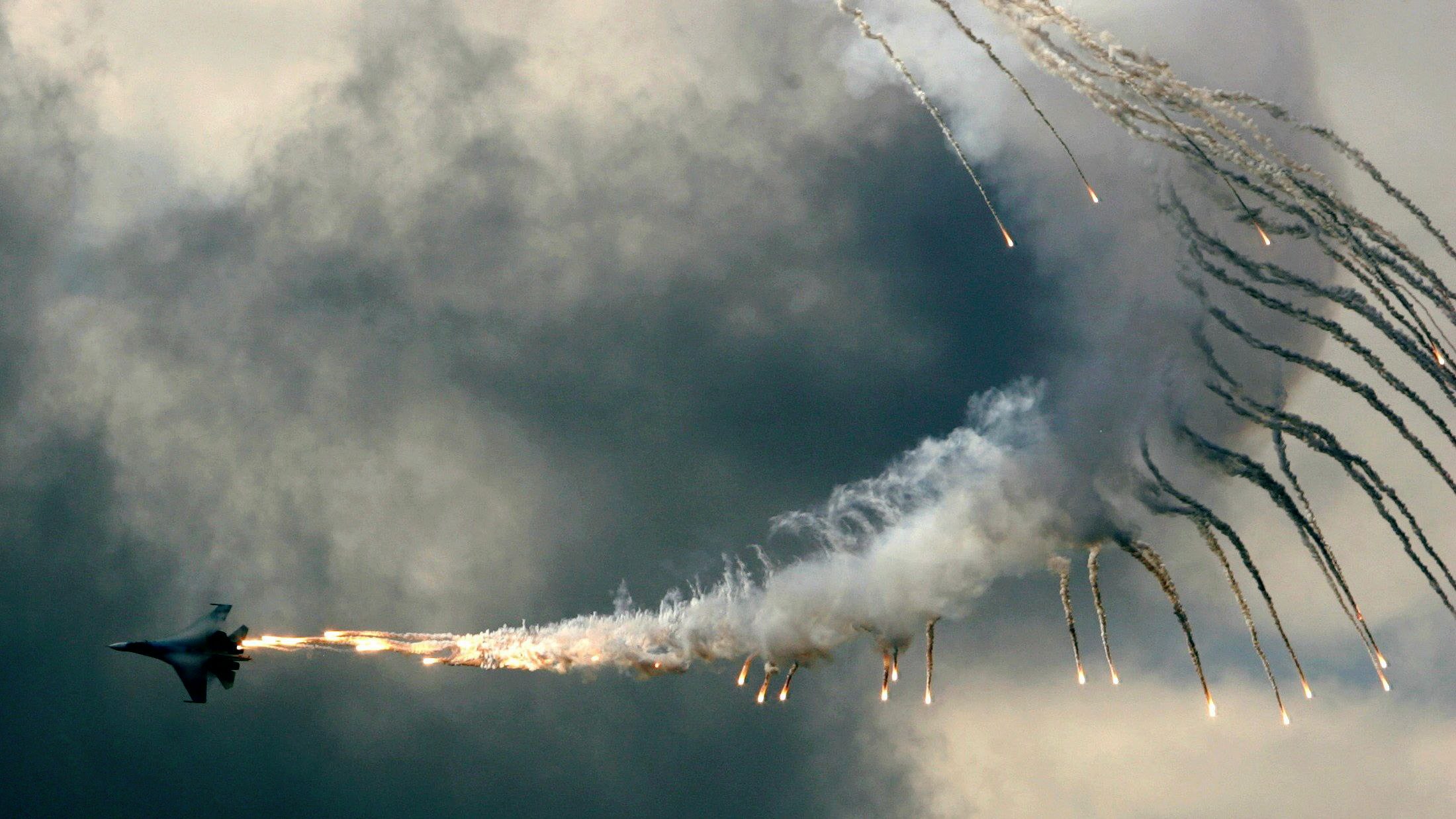 Sukhoi Su-27 releasing flares against cloudy sky HD Wallpaper