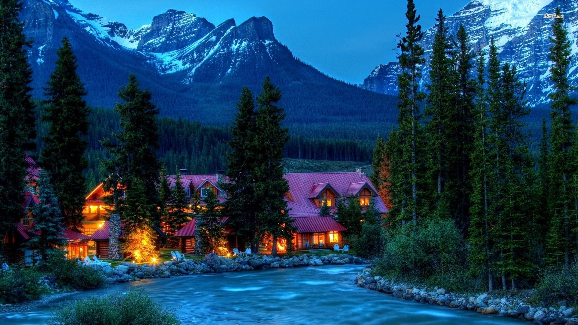 Lodge by a river with mountains and pine trees at dusk HD Wallpaper