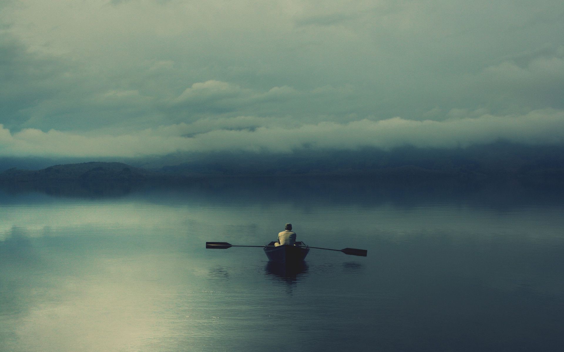 Man rowing a boat on a misty lake HD Wallpaper