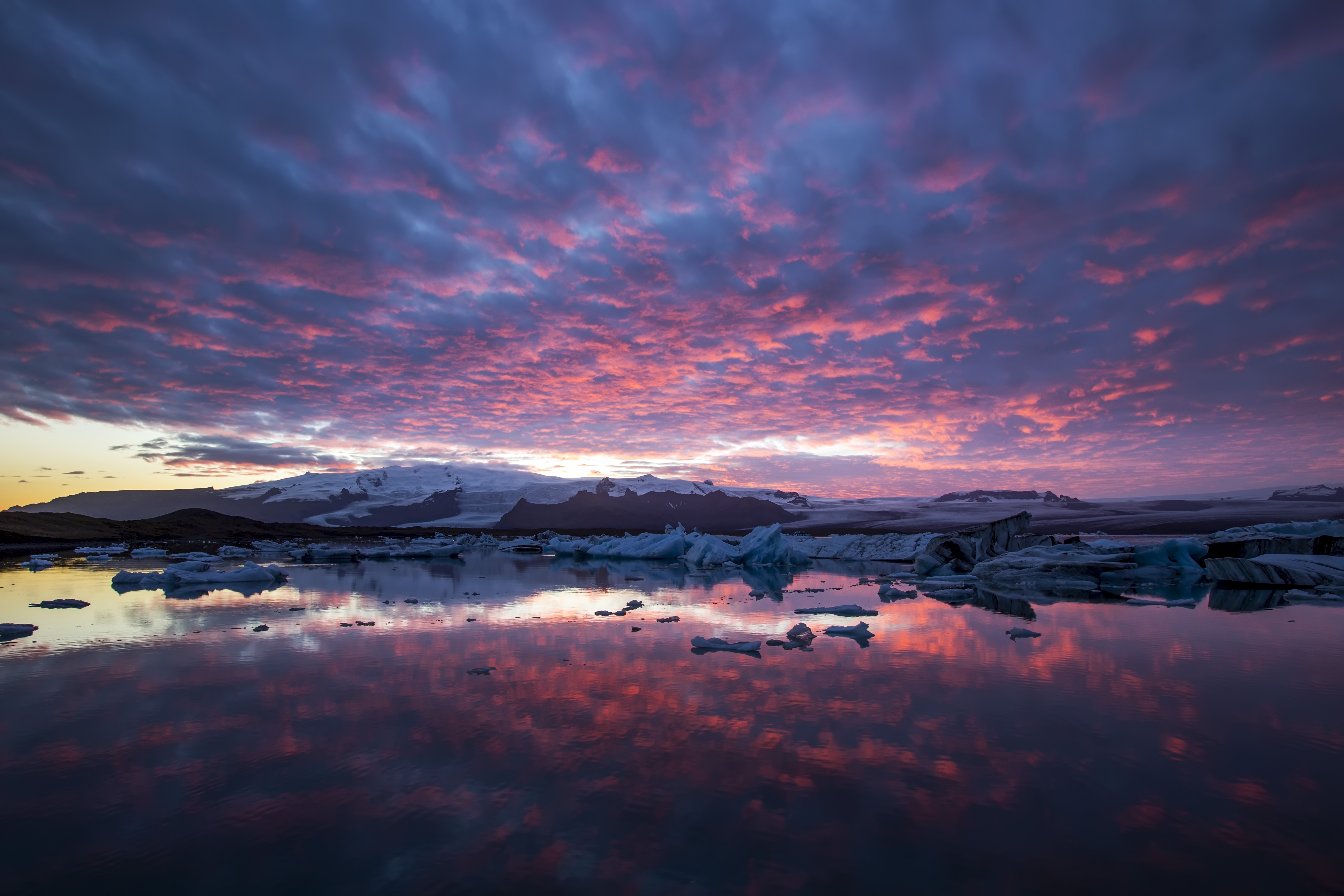 Icebergs floating in a lake with mountains and colorful clouds at sunset HD Wallpaper