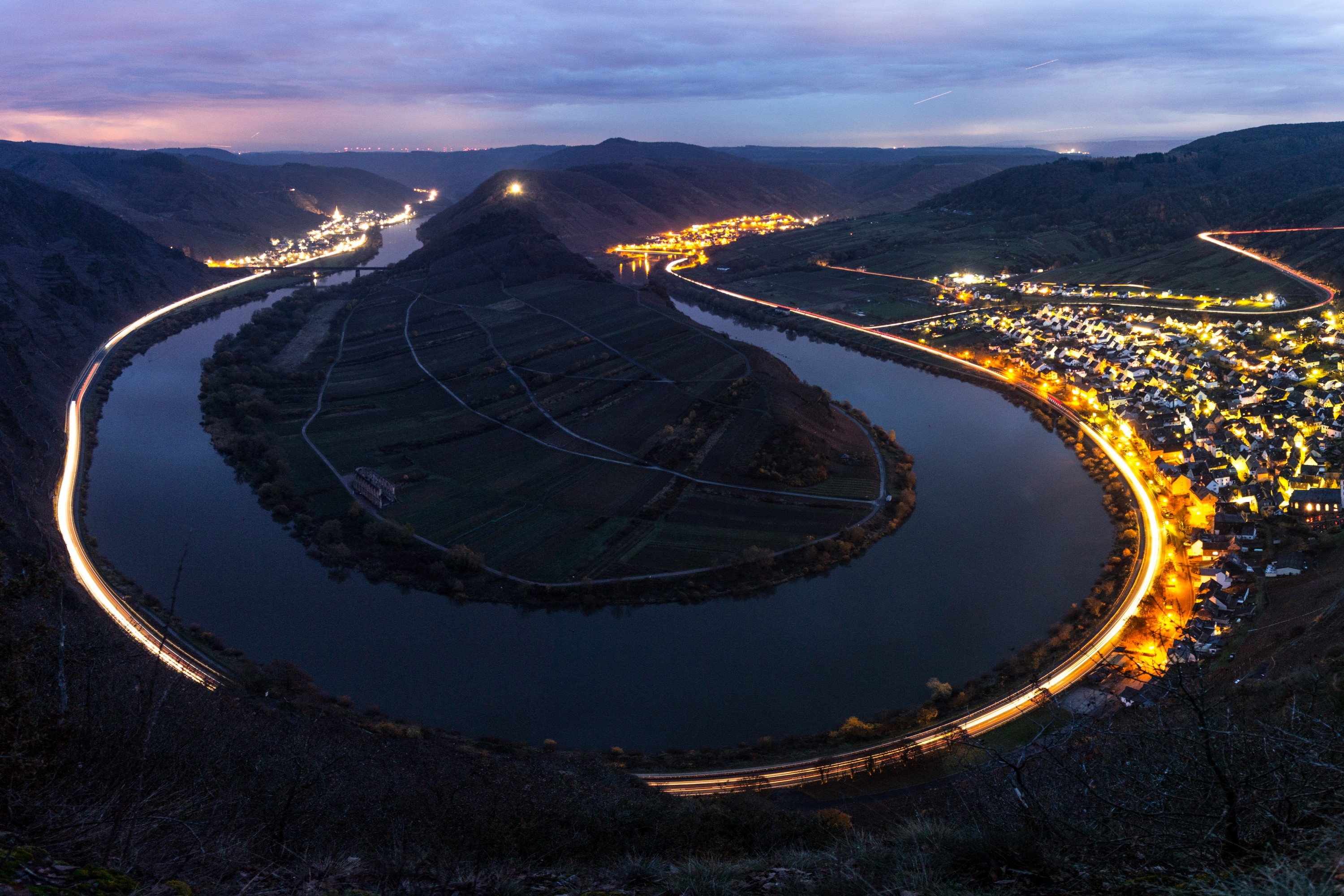 River bend with town lights and light trails at night HD Wallpaper