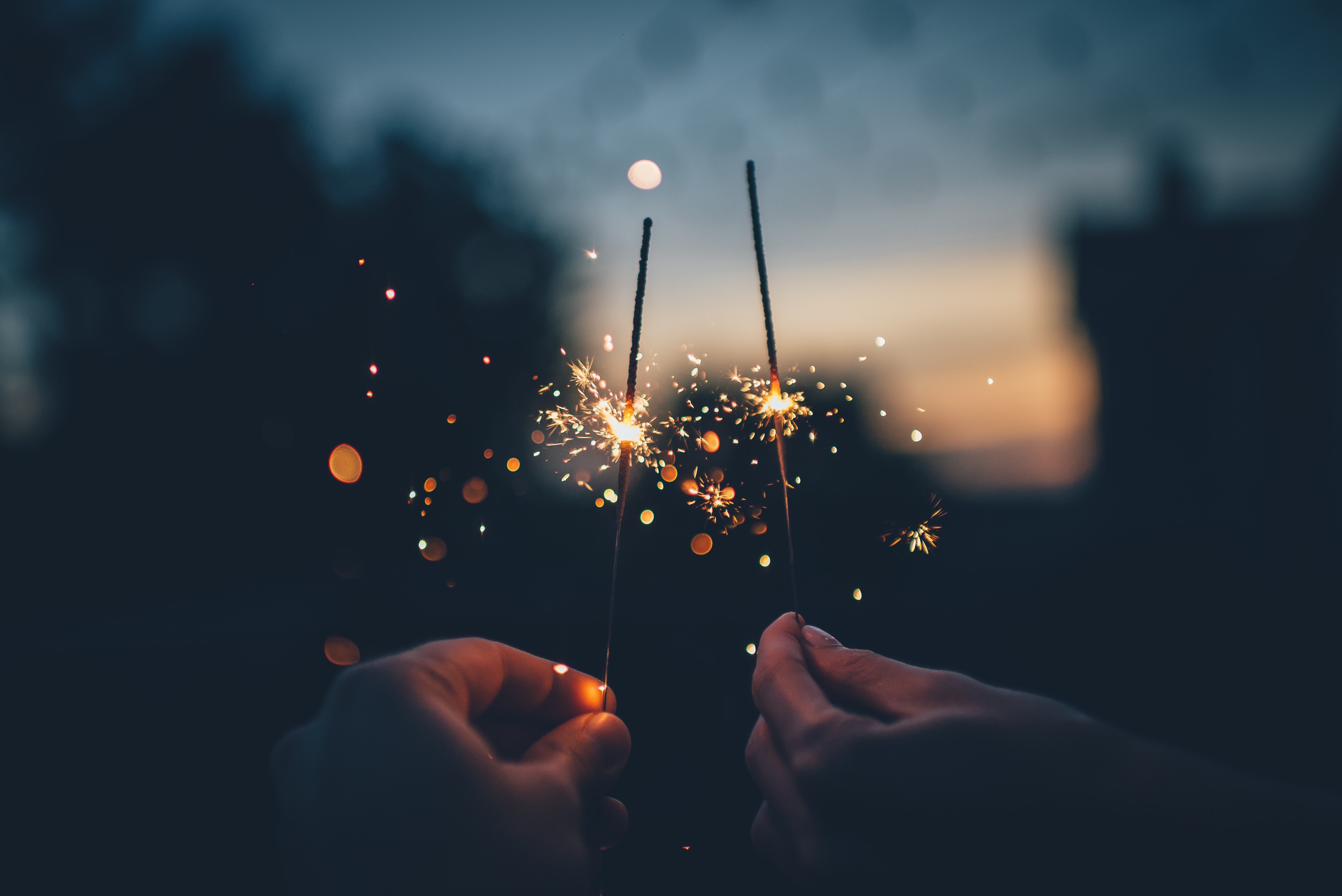 Hands holding sparklers at dusk HD Wallpaper