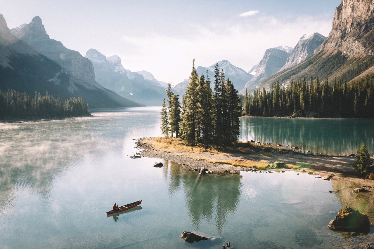 Canoe on a misty lake with mountains and pine trees HD Wallpaper
