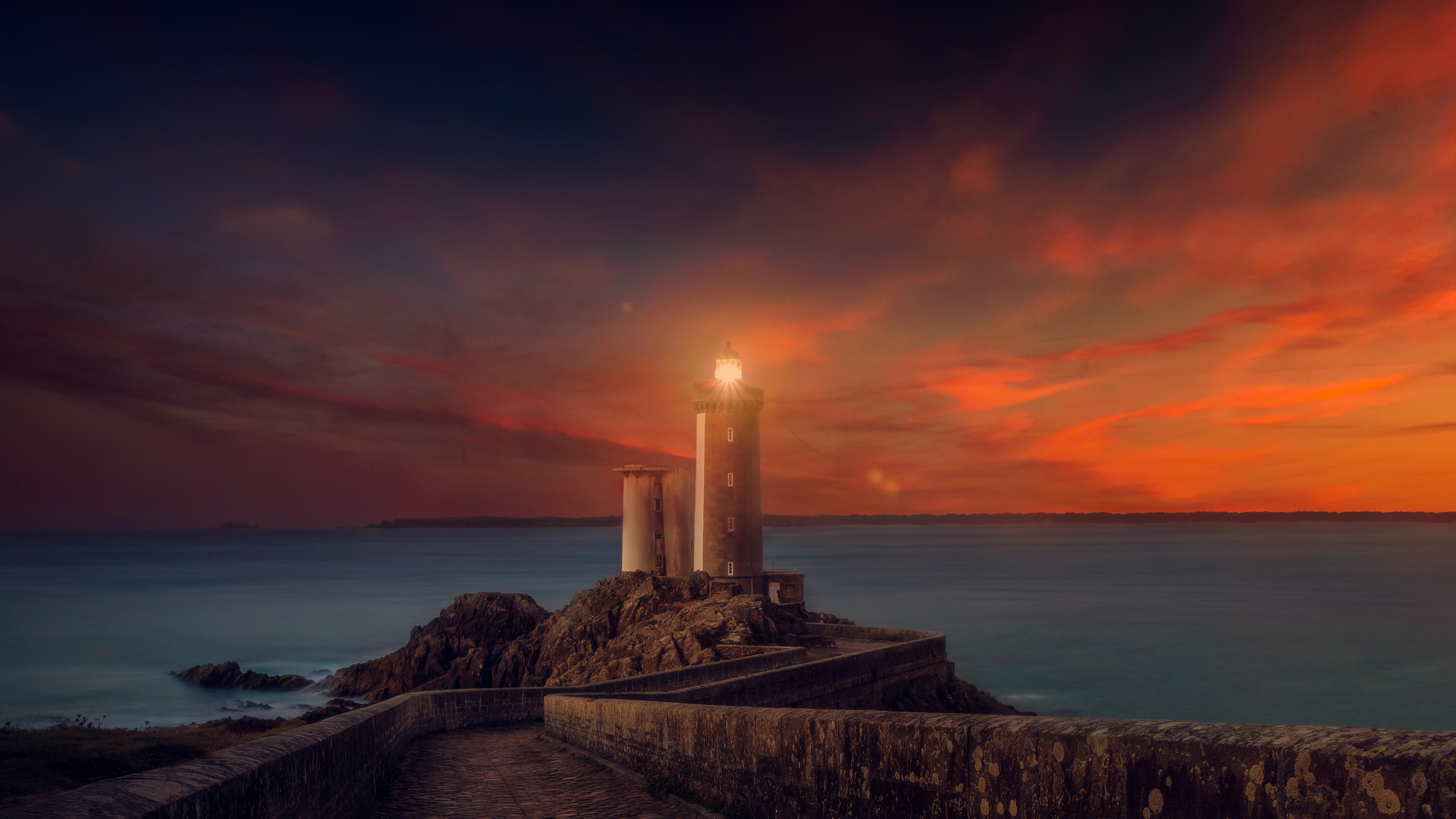 Lighthouse on a rocky island at sunset HD Wallpaper