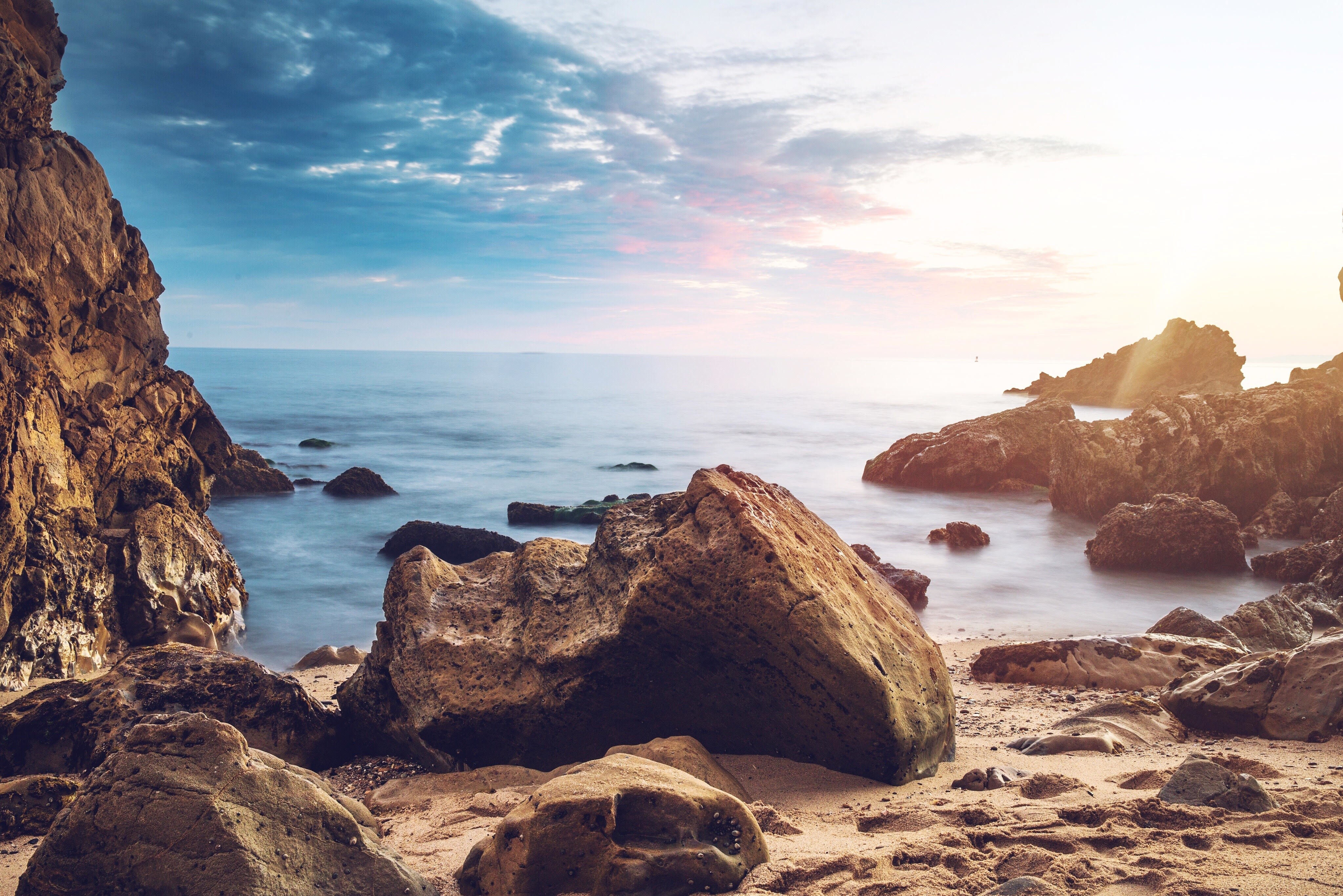 Rocky beach with ocean waves at sunset HD Wallpaper